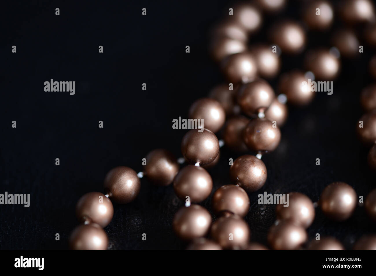 Long necklace of brown beads on a dark background close up Stock Photo