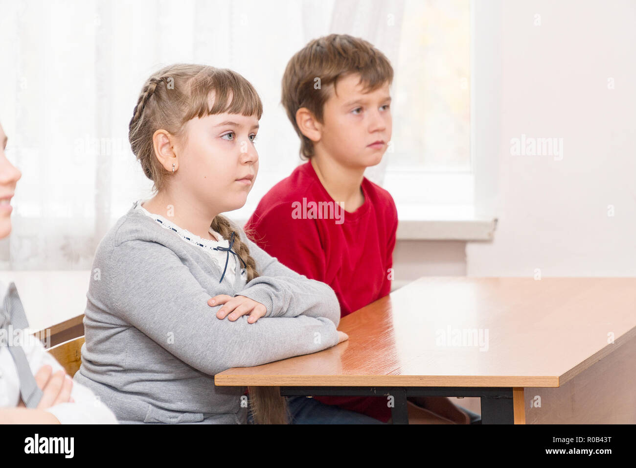 School Kids In The Classroom Sitting At Their Desks And Listen To