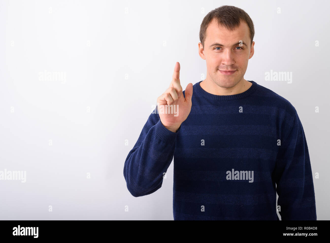 Studio shot of young muscular man pointing finger up against whi Stock Photo