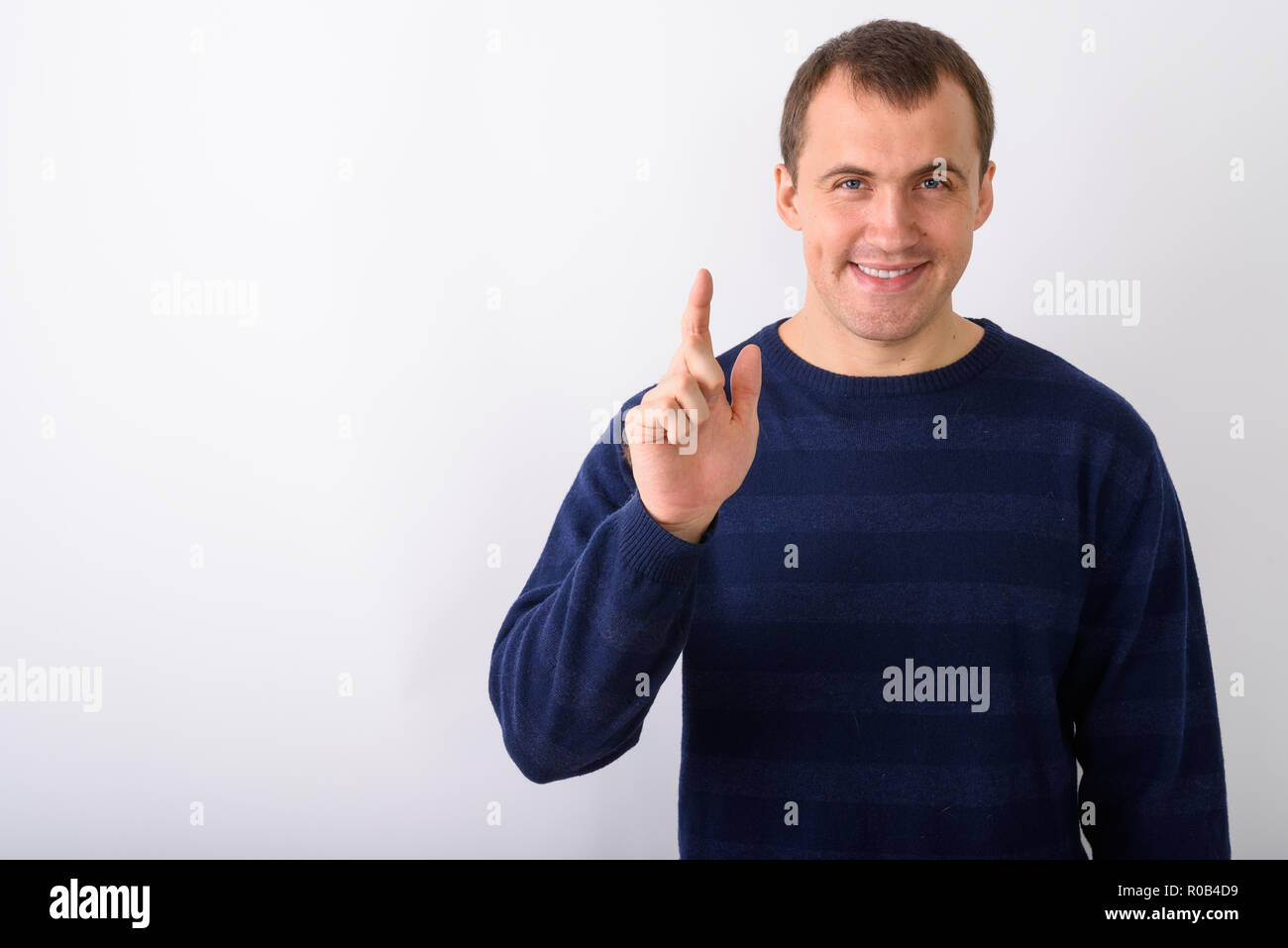 Studio shot of young happy muscular man smiling while pointing f Stock Photo