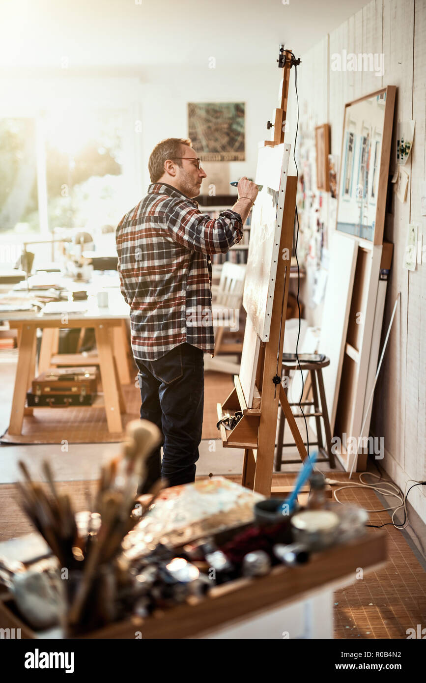 A painter in his studio working on a canvas at sunrise Stock Photo