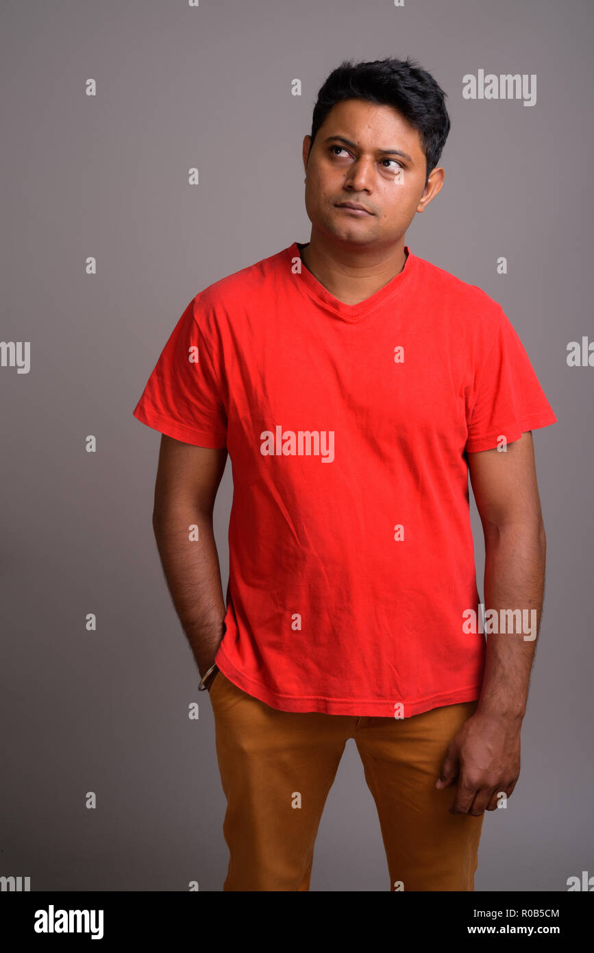 Portrait of young Indian man against gray background Stock Photo