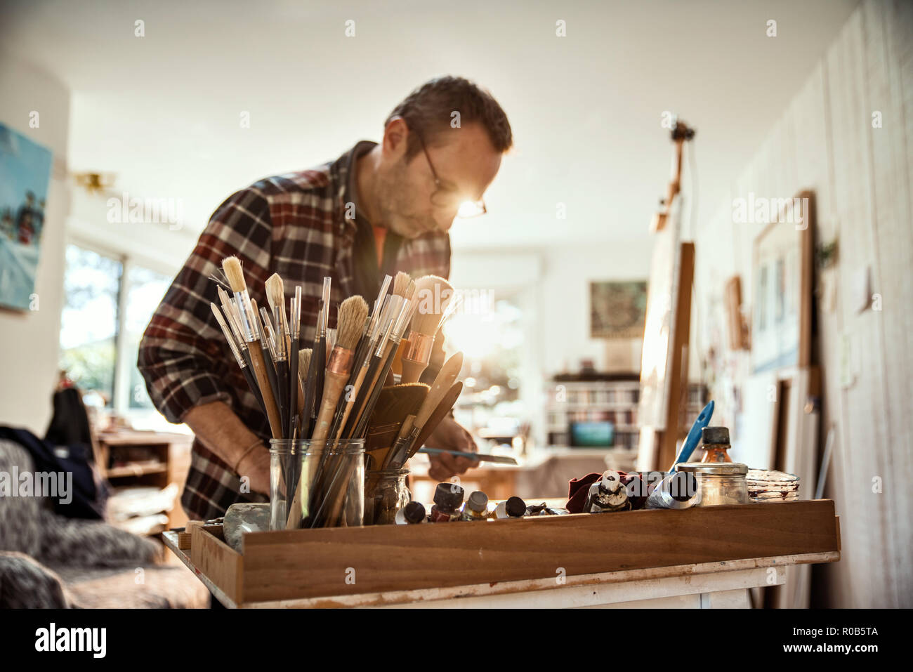 A painter in his studio working on a canvas at sunrise Stock Photo