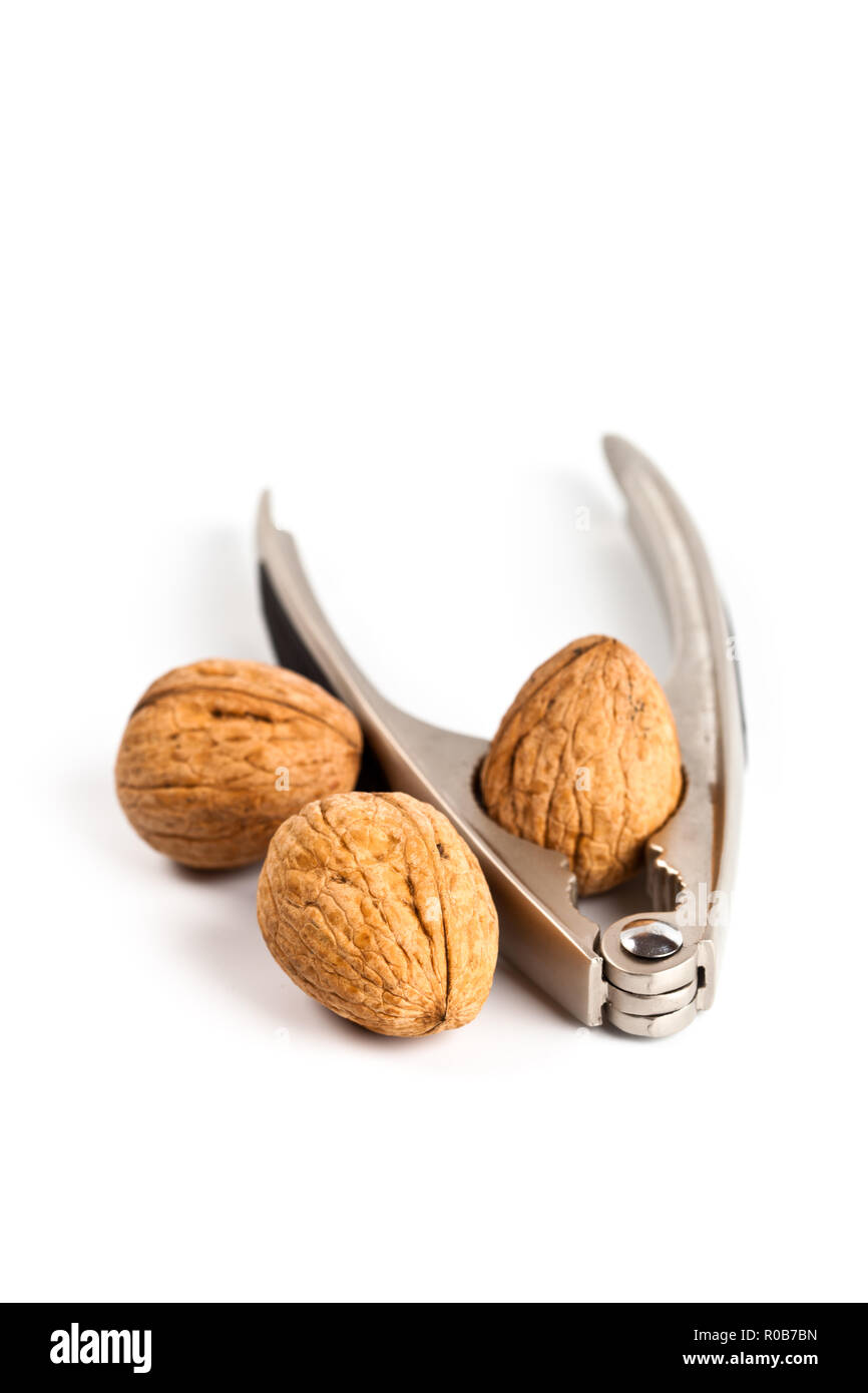 three walnuts and nutcracker on white background Stock Photo