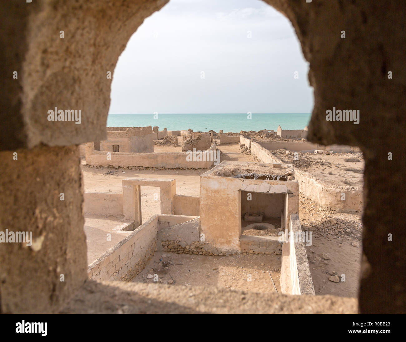 A view out of abandoned Mosque minaret's window to the sea. Ruined ancient old Arab town Al Jumail, Qatar. The desert at coast of Persian Gulf. Stock Photo