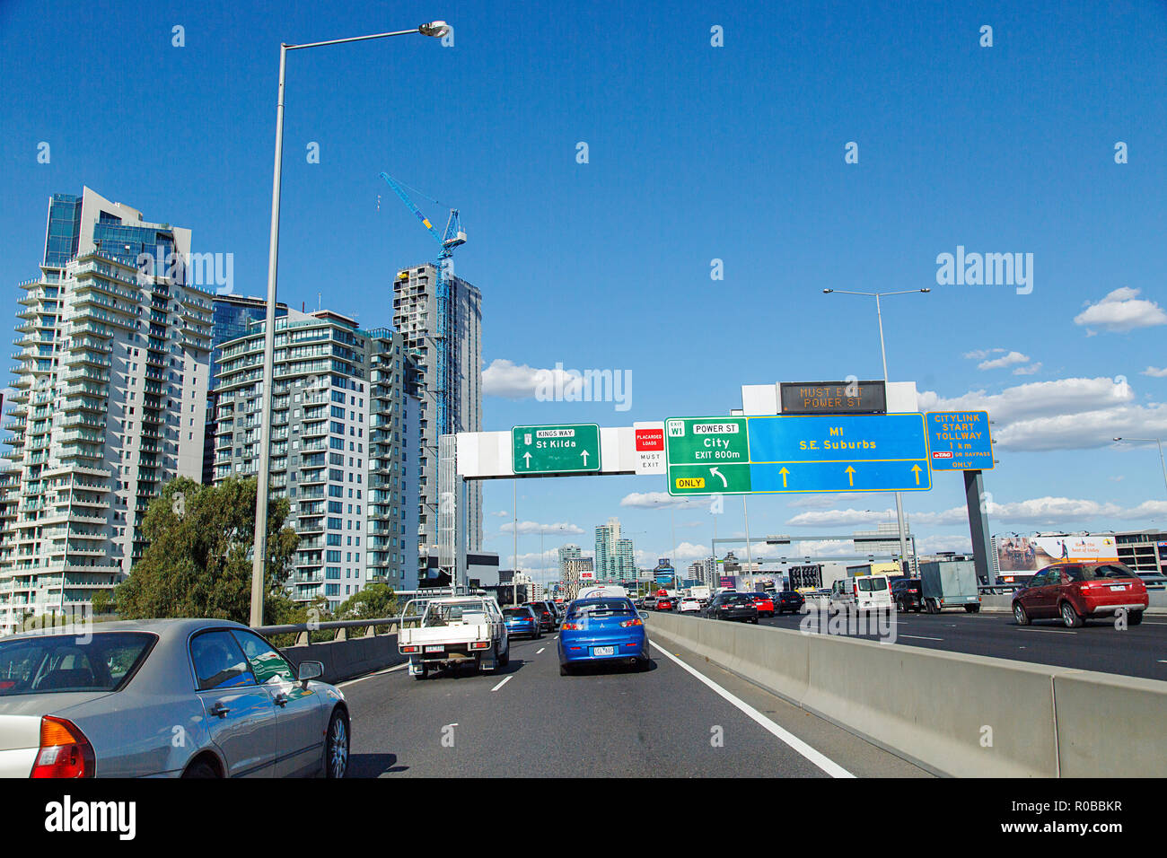 Melbourne, Australia: March 23, 2018: Driving on the west Gate Freeway into Melbourne. Road signs to the suburbs and traffic with a blue sky. Stock Photo