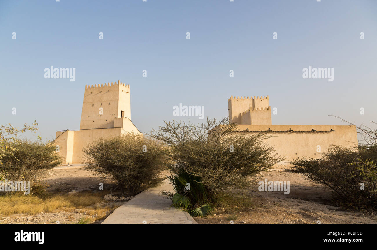 Two Barzan watchtowers behind desert bushes, Umm Salal Mohammed Fort Towers, ancient Arabian fortification, near Doha city, Qatar. Stock Photo