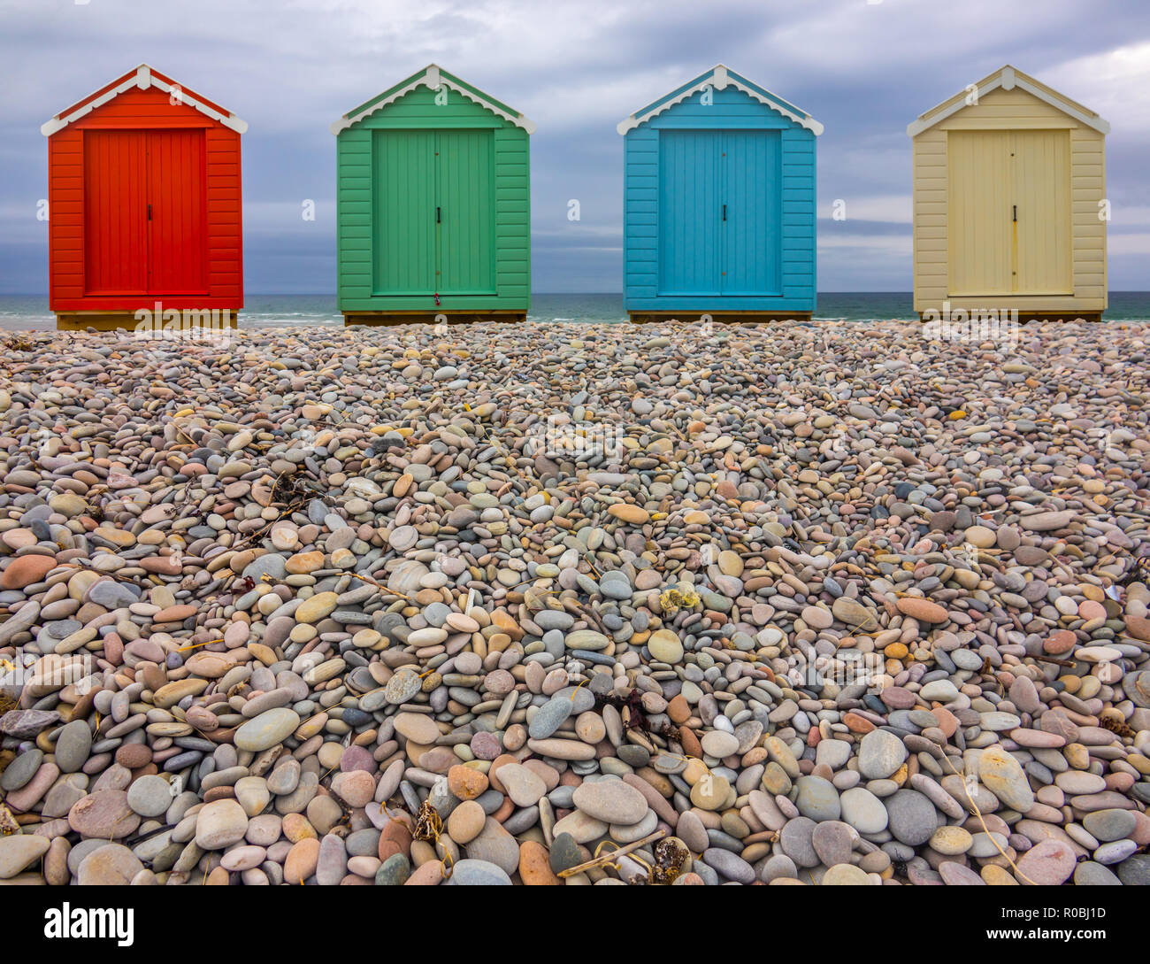Vintage British Beach Huts On A Stony Shore With Wintry Sky With Copy Space (Focus On Foreground) Stock Photo