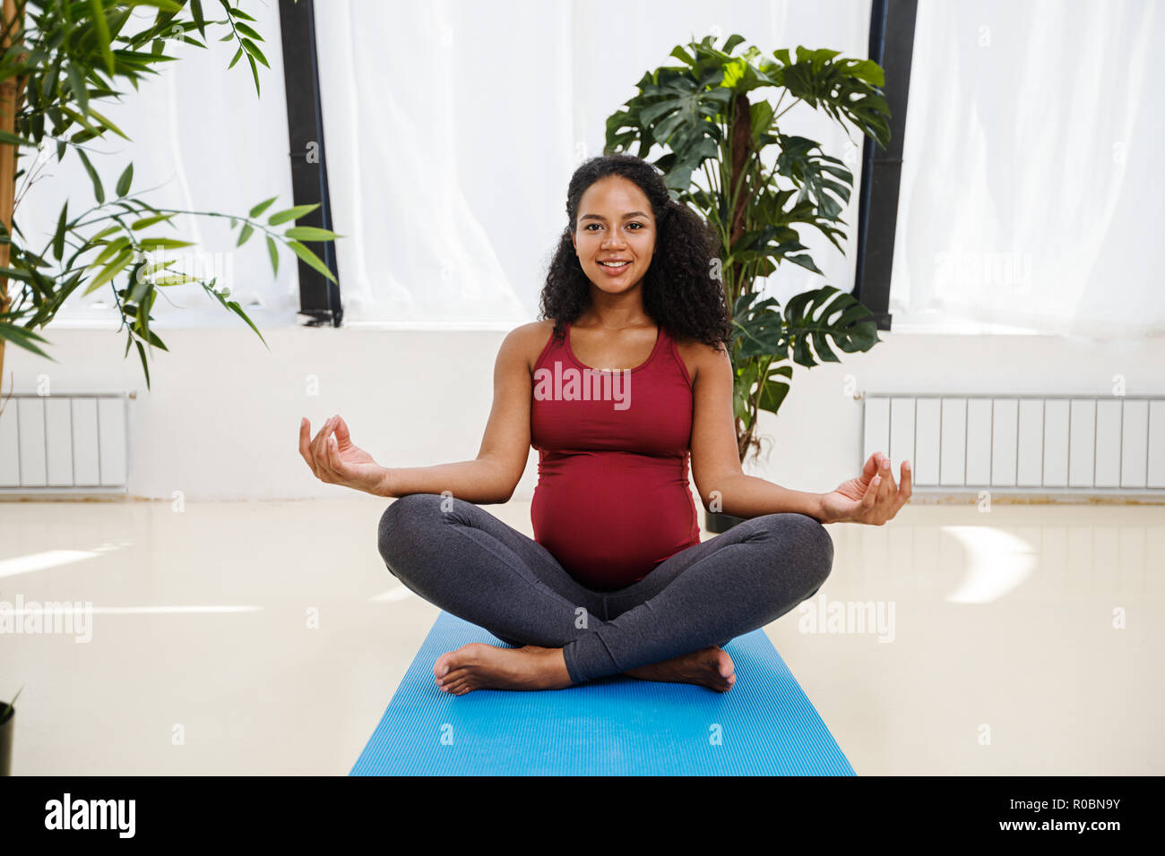 Young beautiful pregnant female meditating in studio Stock Photo