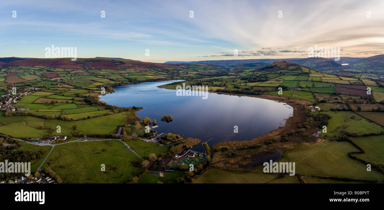 Aerial panoramic view of a beautiful natural lake in Brecon Beacons surrounded by rural farmland