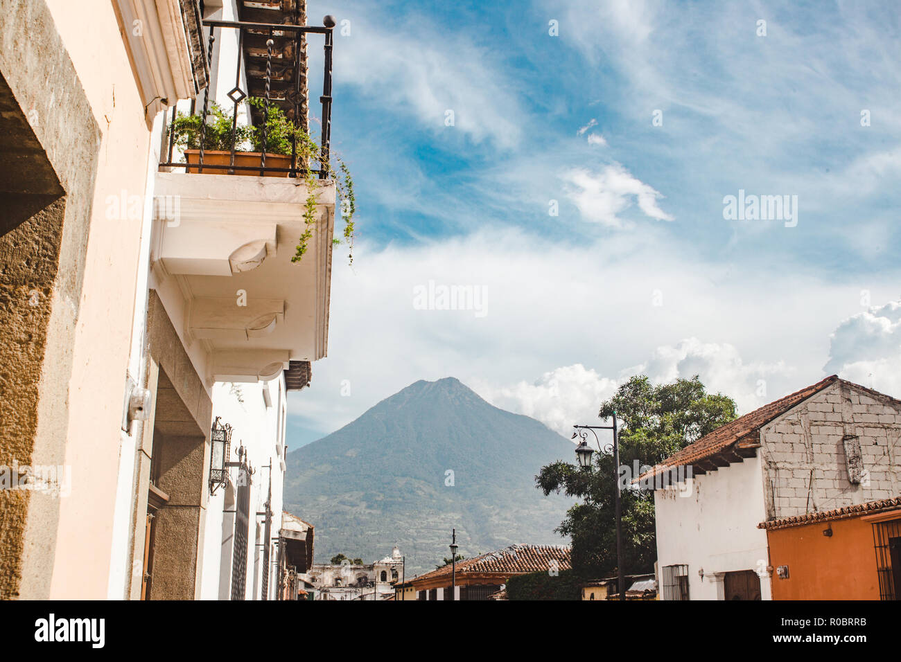 Colorful streets of Antigua Guatemala lead towards the Volcan de Agua Volcano on a summer's day Stock Photo