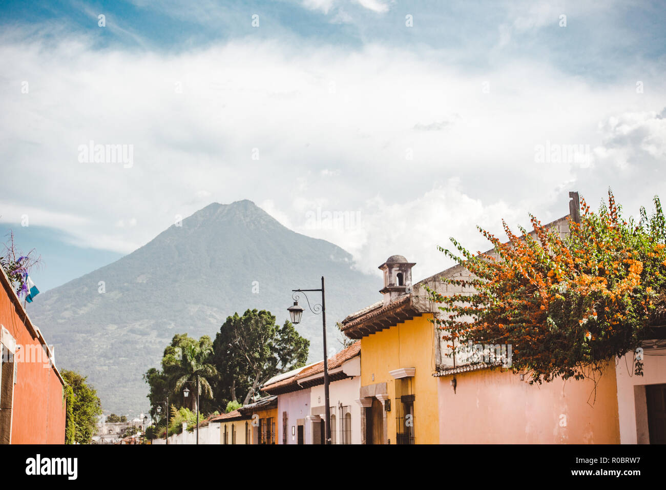 Colorful streets of Antigua Guatemala lead towards the Volcan de Agua Volcano on a summer's day Stock Photo