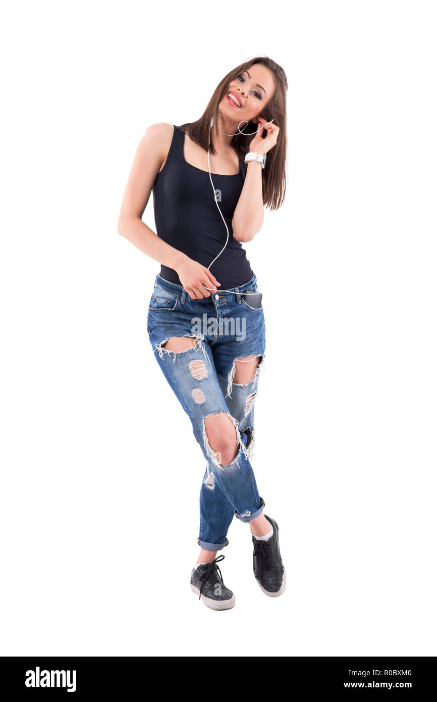 Charming pretty young happy woman listening music with mobile phone earphones smiling. Full body isolated on white background. Stock Photo