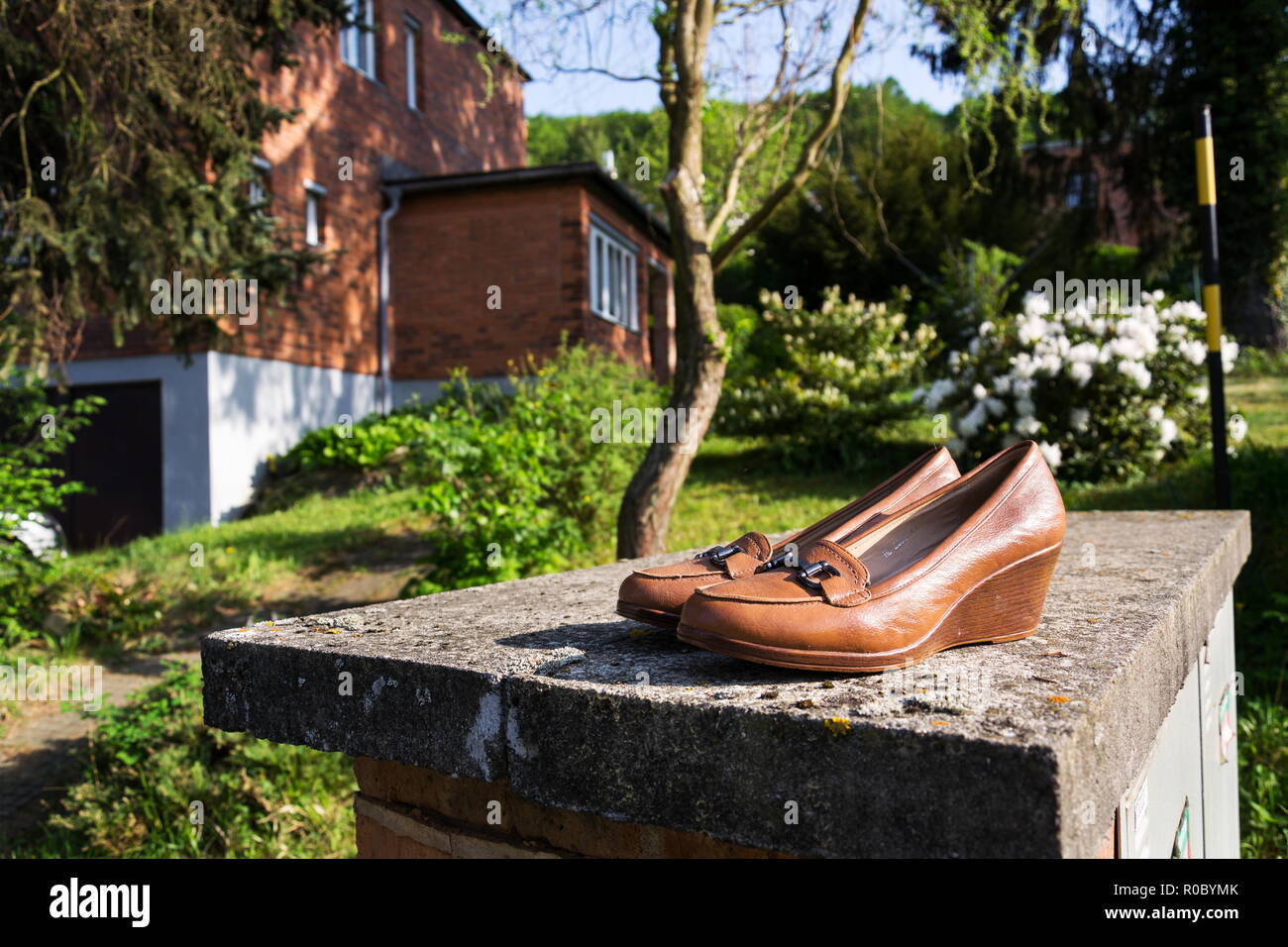 Old vintage shoes with typified red brick family Bata house in background, Zlin, Moravia, Czech Republic, sunny summer day Stock Photo