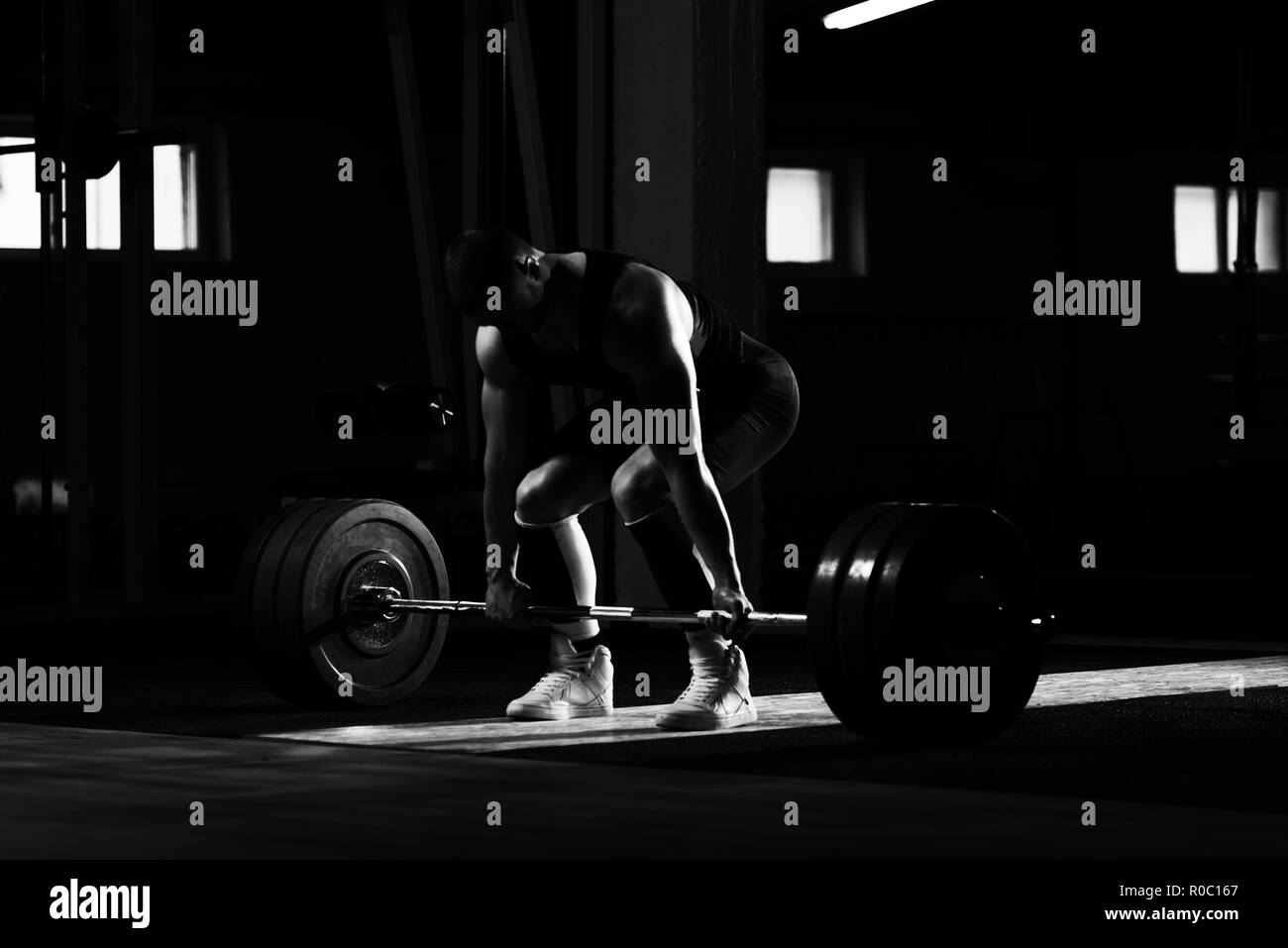 Athlete Is Standing on His Knee and Near the Bar in the Gym and Is Preparing to Make a Deadlift Stock Photo