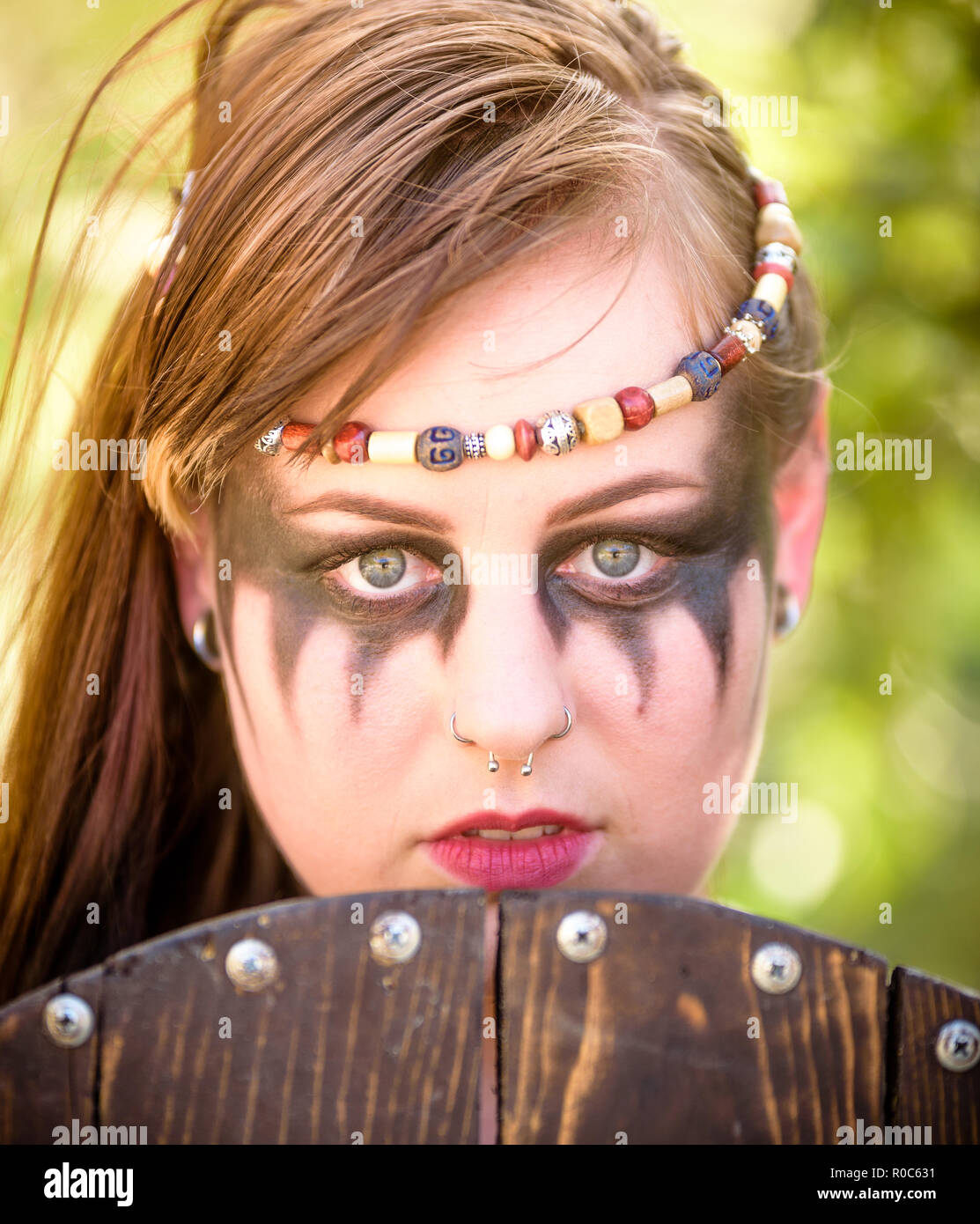 A beautiful female shield maiden viking character with fur and an ax in the foothills of a mountain. Fashion editorial influences Stock Photo