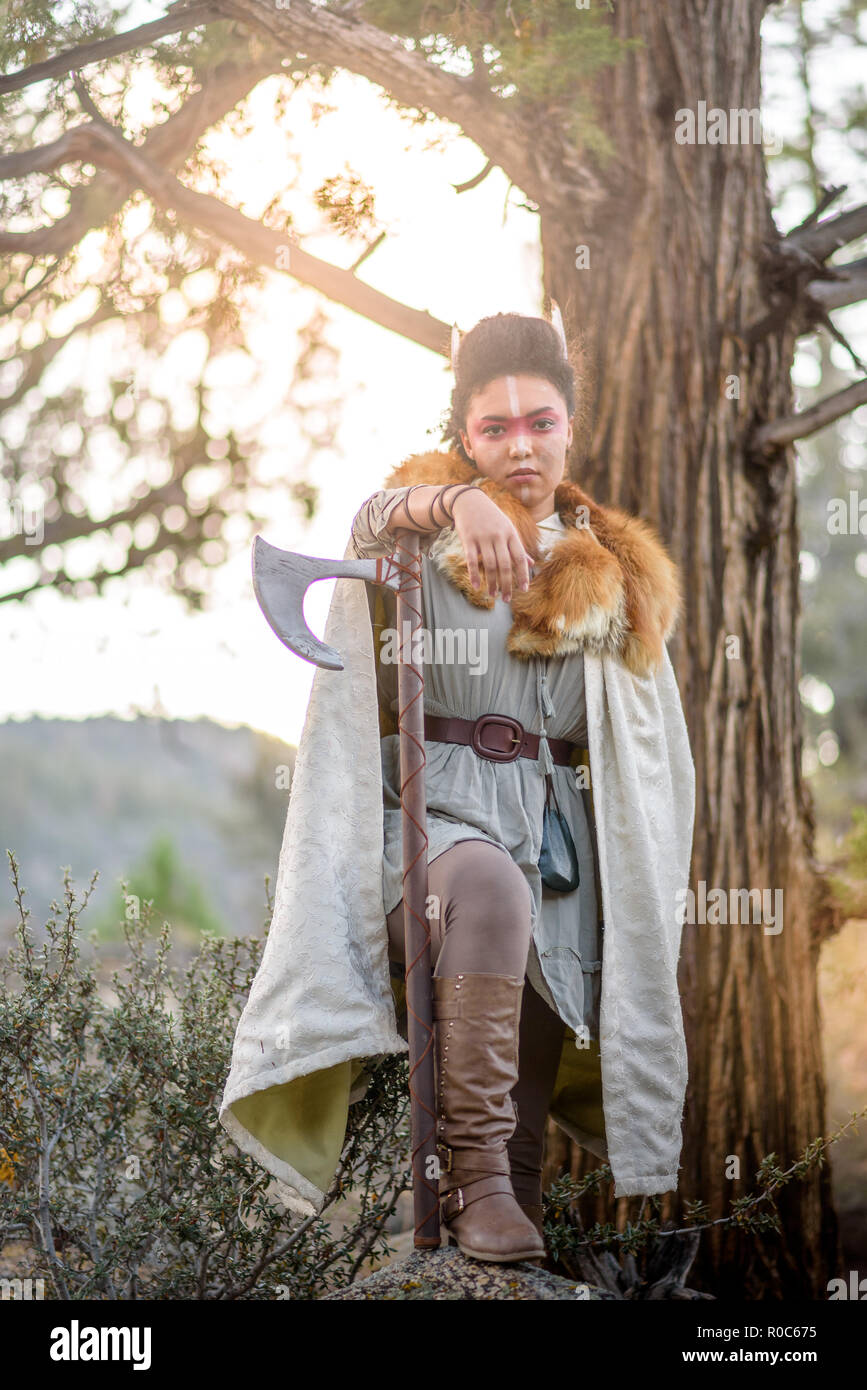 A beautiful female shield maiden viking character with real fur and an axe in the mountains. Fashion editorial influences Stock Photo