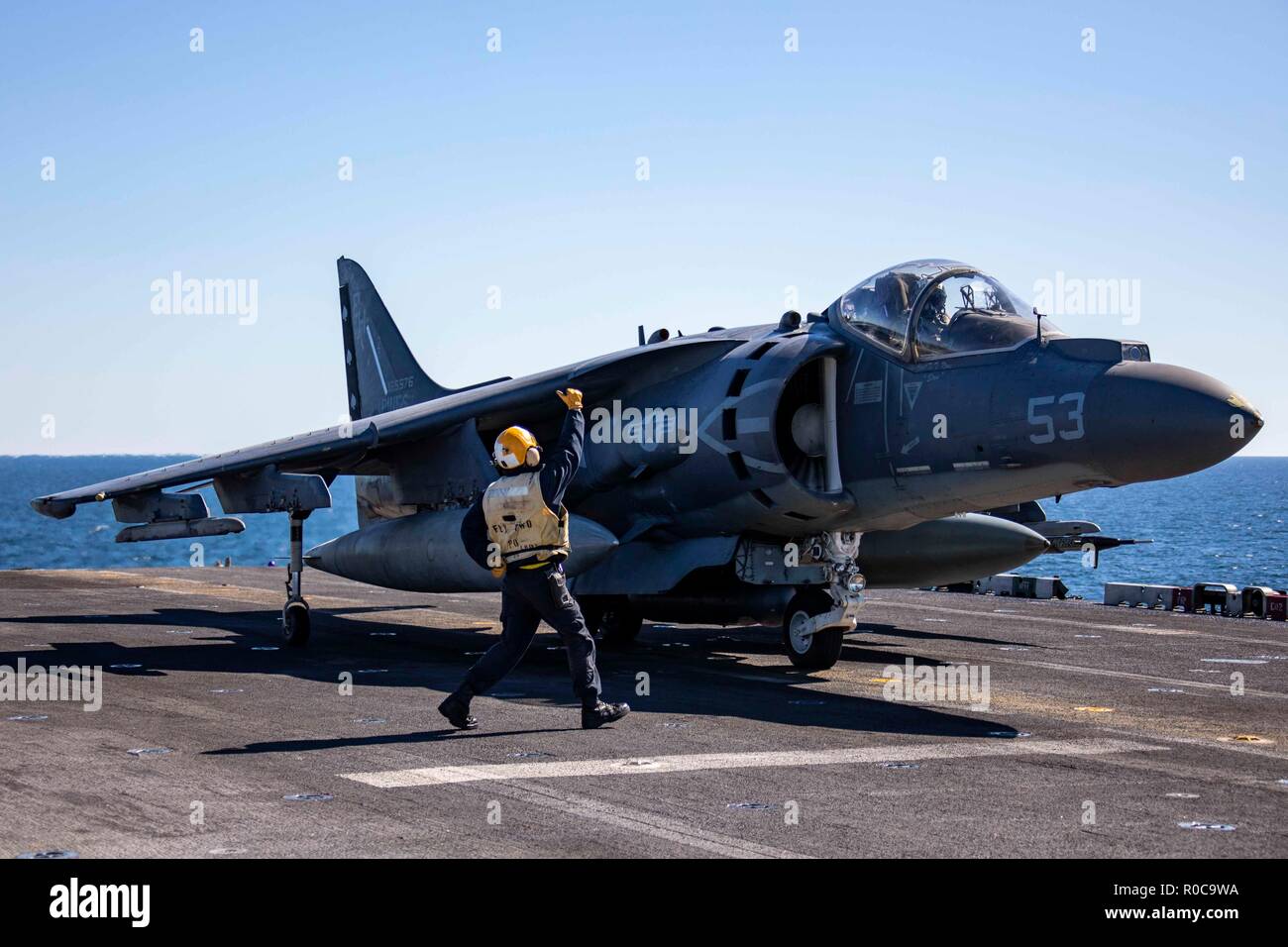 181029-N-KW492-0213 ATLANTIC OCEAN (Oct. 29, 2018) Aviation Boatswain's Mate (Handling) 2nd Class Reymond Rallos signals to the pilot of an AV-8B Harrier on the flight deck of the Wasp-class amphibious assault ship USS Kearsarge (LHD3) during the Carrier Strike Group (CSG) 4 composite training unit exercise (COMPTUEX). COMPTUEX is the final pre-deployment exercise that certifies the combined Kearsarge Amphibious Ready Group's and 22nd Marine Expeditionary Unit's abilities to conduct military operations at sea and project power ashore through joint planning and execution of challenging and real Stock Photo