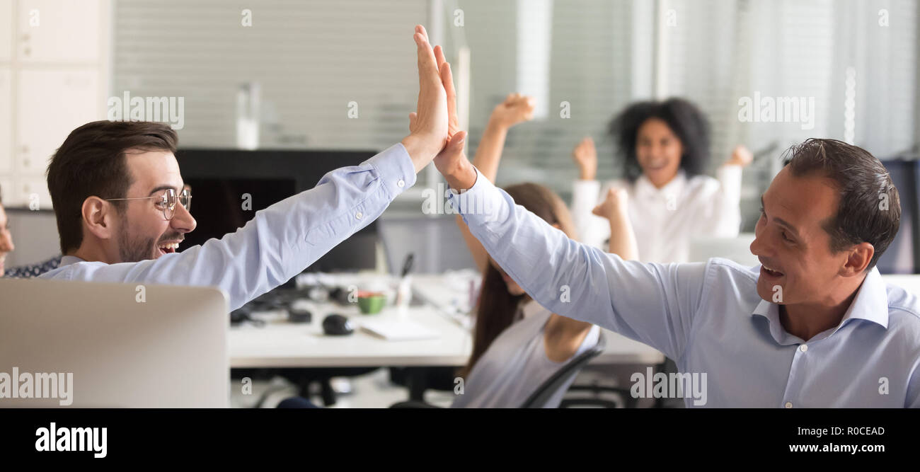Excited euphoric male colleagues giving high five celebrating br Stock ...