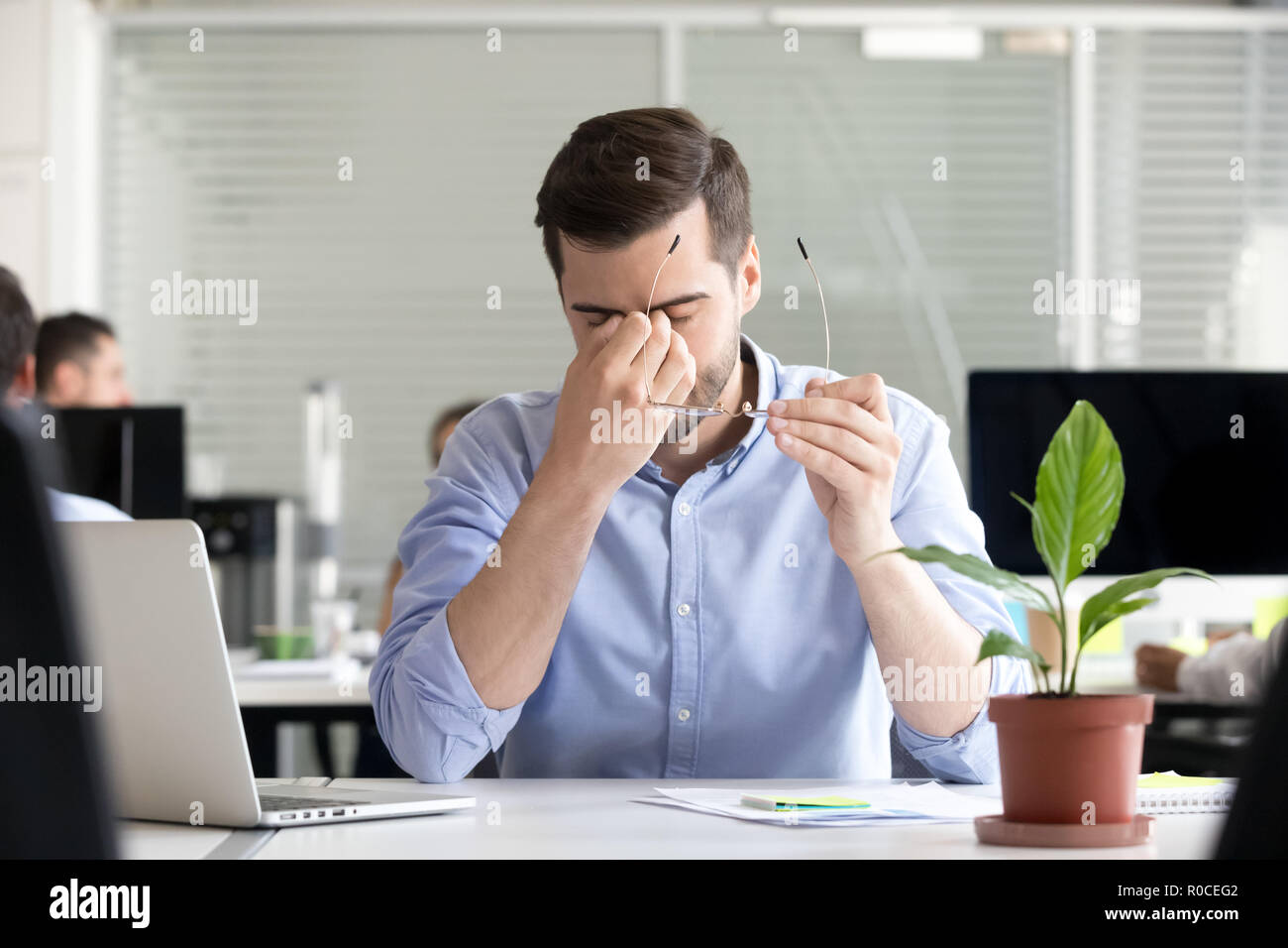 Tired businessman taking off glasses to relieve dry irritated ey Stock