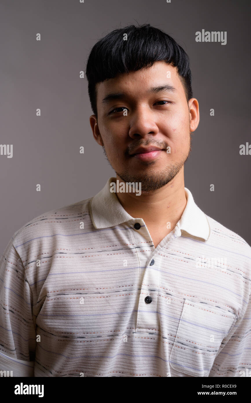 Portrait Of Young Asian Man Against Gray Background Stock