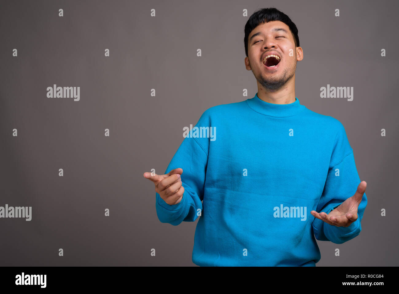 Portrait of young Asian man against gray background Stock Photo