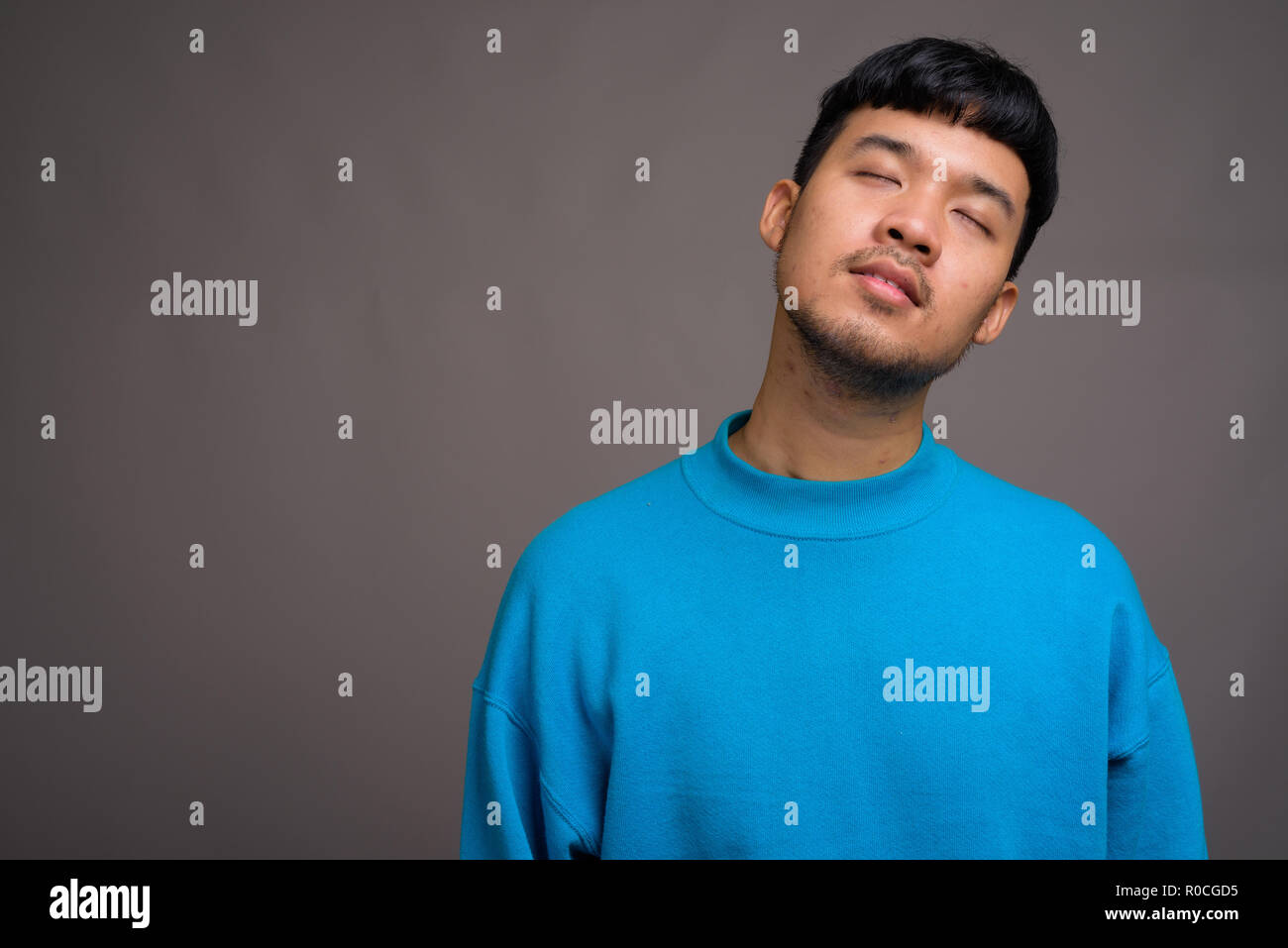 Portrait of young Asian man against gray background Stock Photo