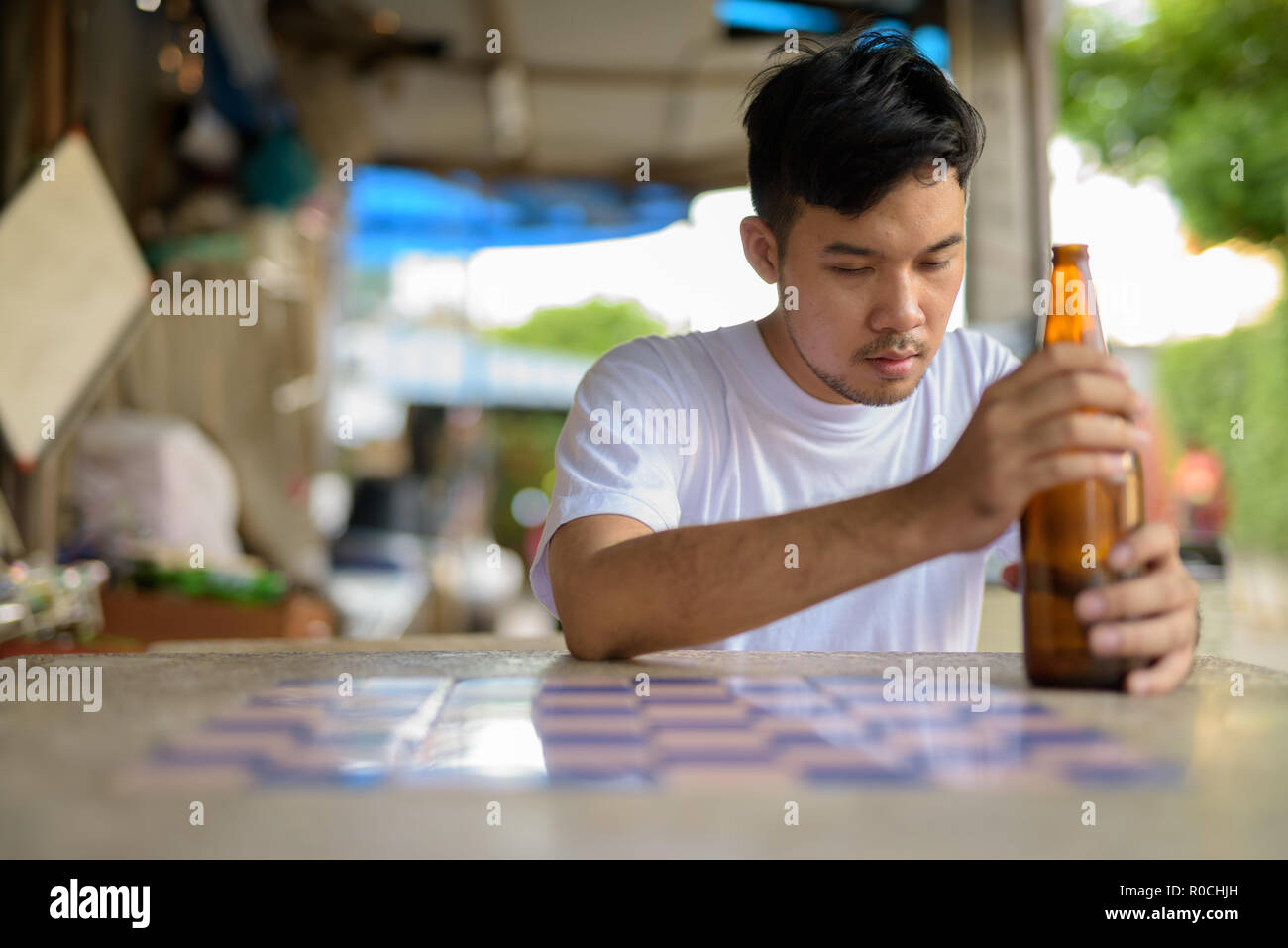 Young Asian man getting drunk in the streets outdoors Stock Photo