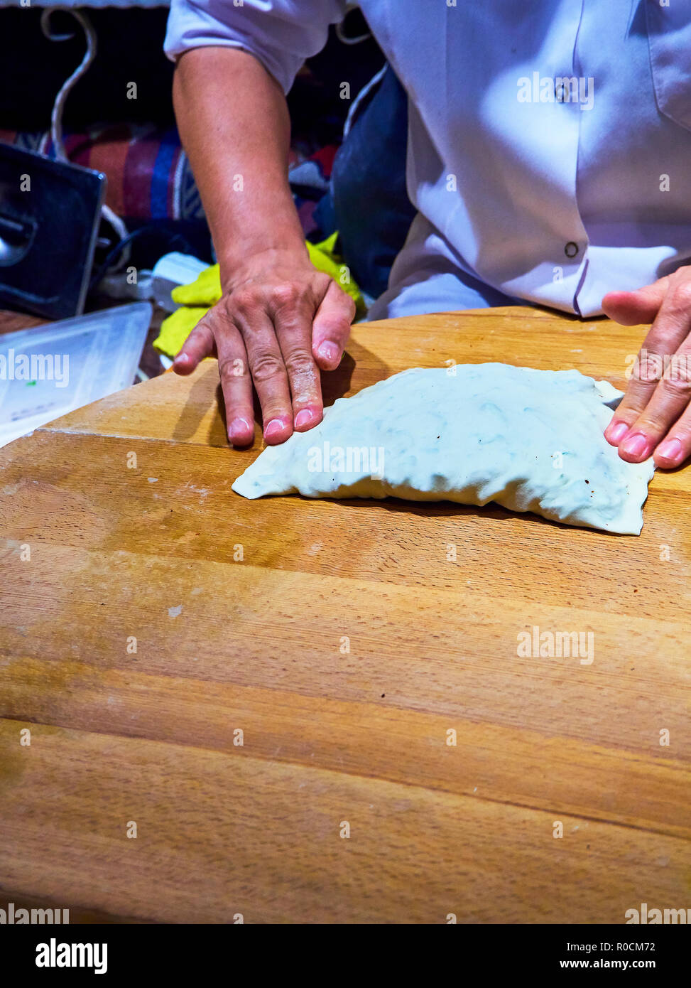 A cook making Turkish Gozleme, a traditional Anatolian stuffed flatbread, cooked over a wood fire on a griddle. Stock Photo