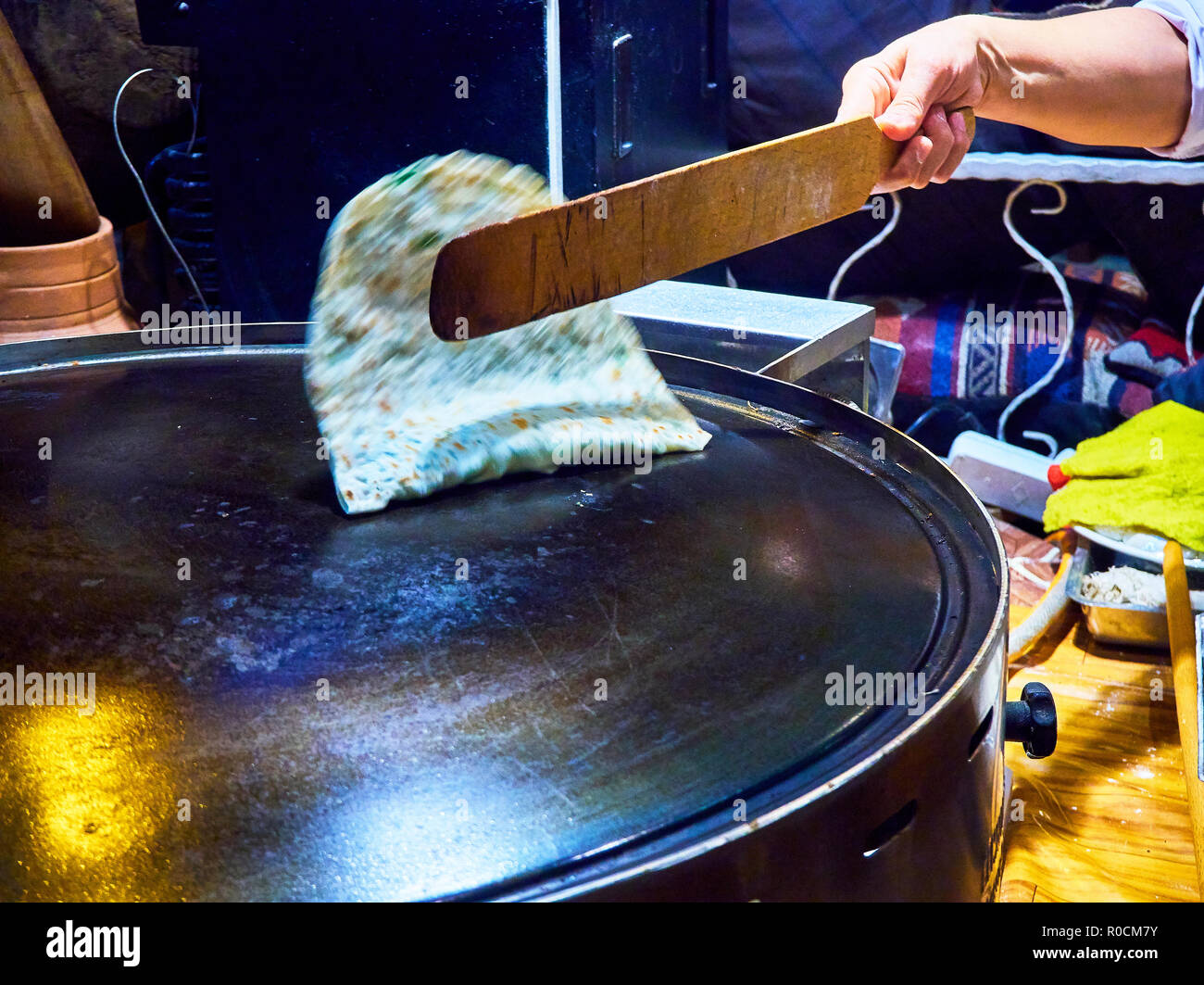 A cook making Turkish Gozleme, a traditional Anatolian stuffed flatbread, cooked over a wood fire on a griddle. Stock Photo