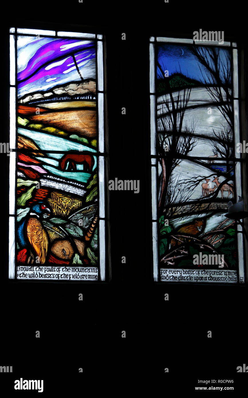 Norman church, St Bartholemew's and the Manor House, Cotswolds village of Notgrove, Gloucestershire. New stained glass depicting autumn and Winter Stock Photo