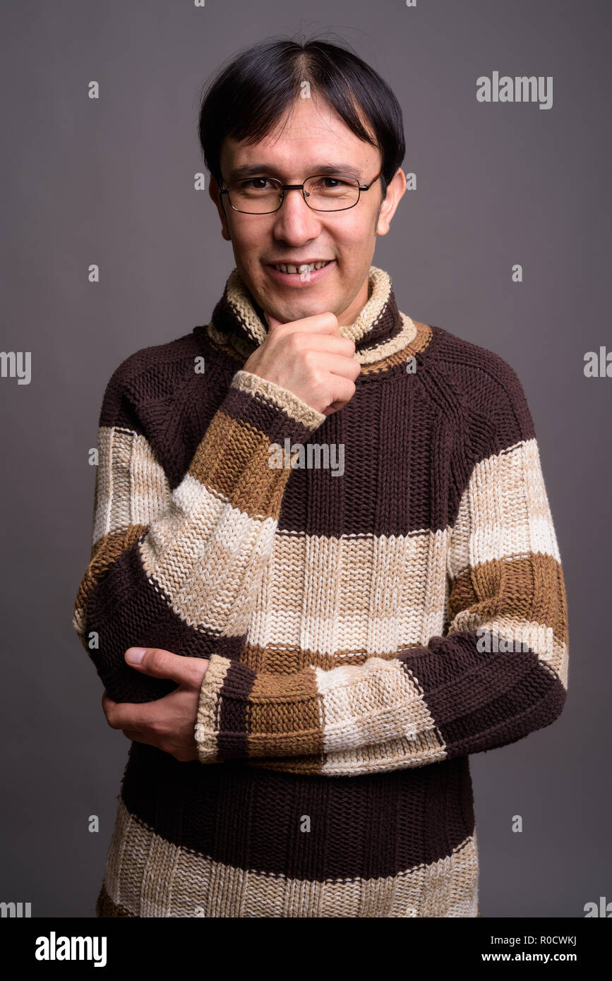 Young Asian nerd man wearing turtleneck sweater against gray bac Stock Photo