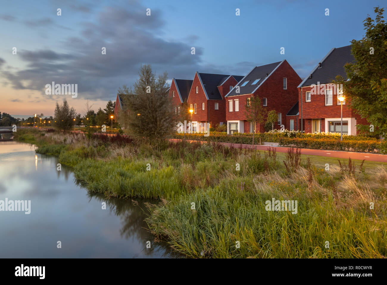 Long exposure night image of a suburban Street with modern ecological middle class family houses with eco friendly river bank in Veenendaal city, Neth Stock Photo