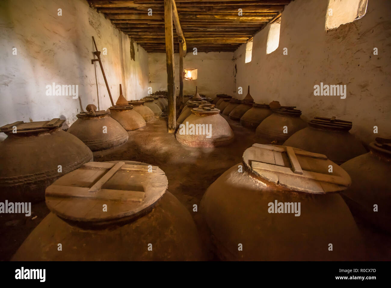 Dark brown old historic Olive oil storage cellar with ceramic pots in Greece Stock Photo