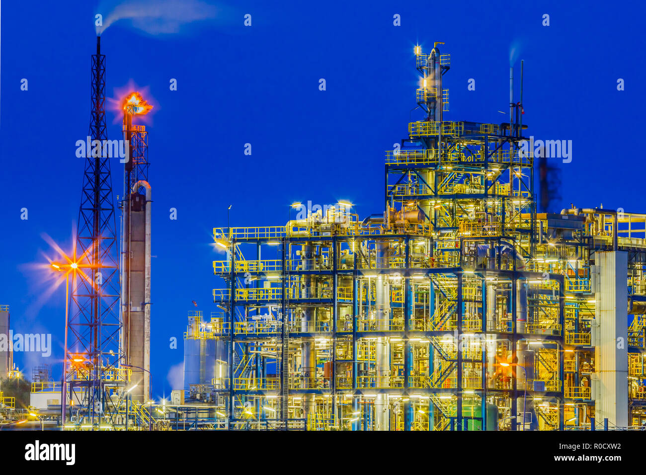 Night scene of a heavy Chemical Industrial plant framework with maze of tubes and pipes during twilight Stock Photo