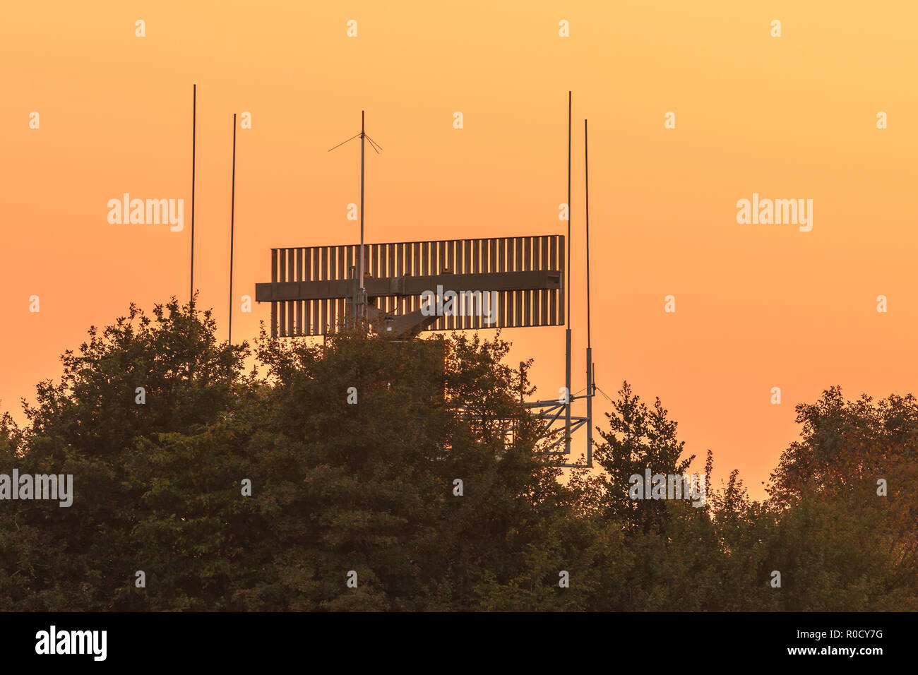 Civil radar antenna communication technology network hidden in bush during sunset. Stock Photo