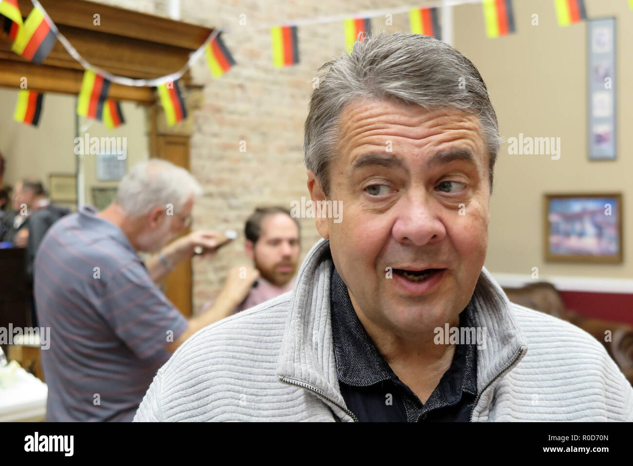 Martinsburg, USA. 03rd Nov, 2018. Former Federal Foreign Minister Sigmar Gabriel (SPD) talks to visitors in 'Uncle Joe's Barbershop'. In honour of Gabriel's visit, the owner has hung up small German flags. Gabriel visited the US state of West Virginia, a stronghold of US President Trump. He wanted to talk to the people there to understand why Trump had so much support there. He did it in Uncle Joe's Barbershop, among other places. (to dpa ''Sigmar from Germany'' - Gabriel visiting Trump-Land' from 04.11.2018) Credit: Can Merey/dpa/Alamy Live News Stock Photo
