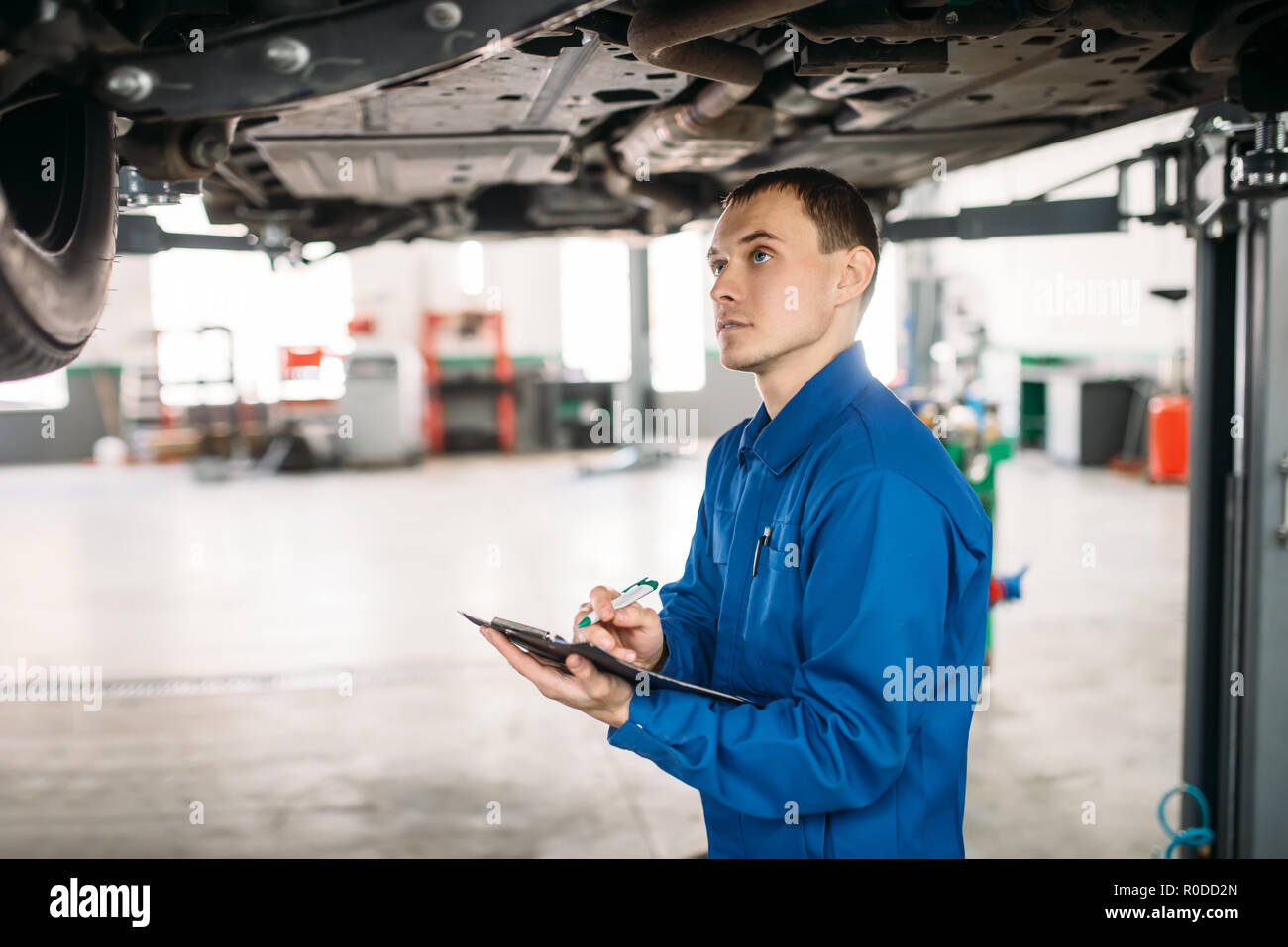 Technician with notebook fills the check list, car on the lift, fixing