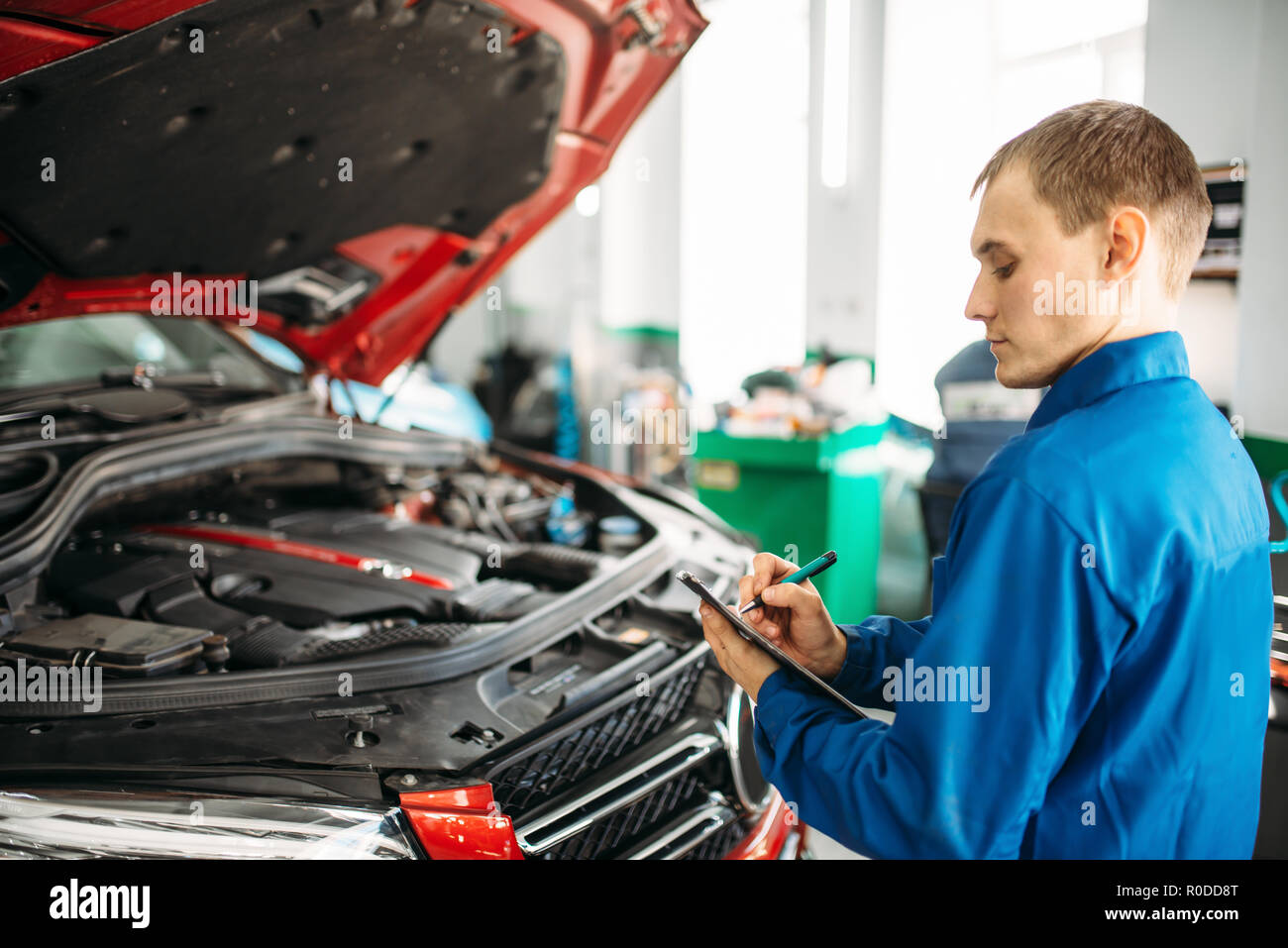 Technician with notebook fills the check list, car with opened hood, fixing  the problems. Automobile service, vehicle maintenance Stock Photo - Alamy