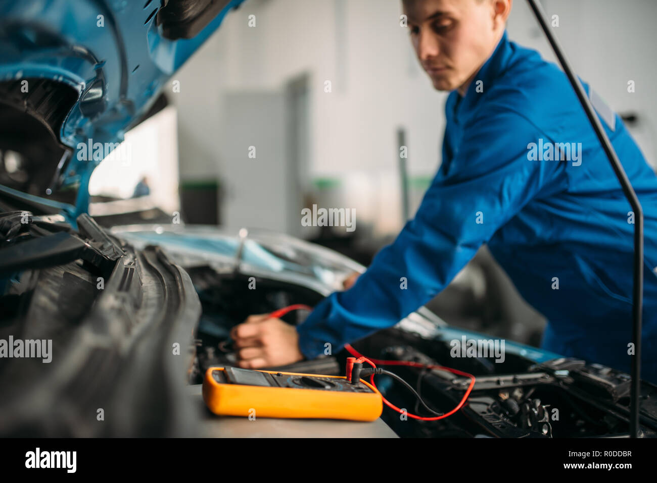 Car repairman with multimeter, battery inspection. Auto-service, vehicle wiring diagnostic, electrician occupation Stock Photo