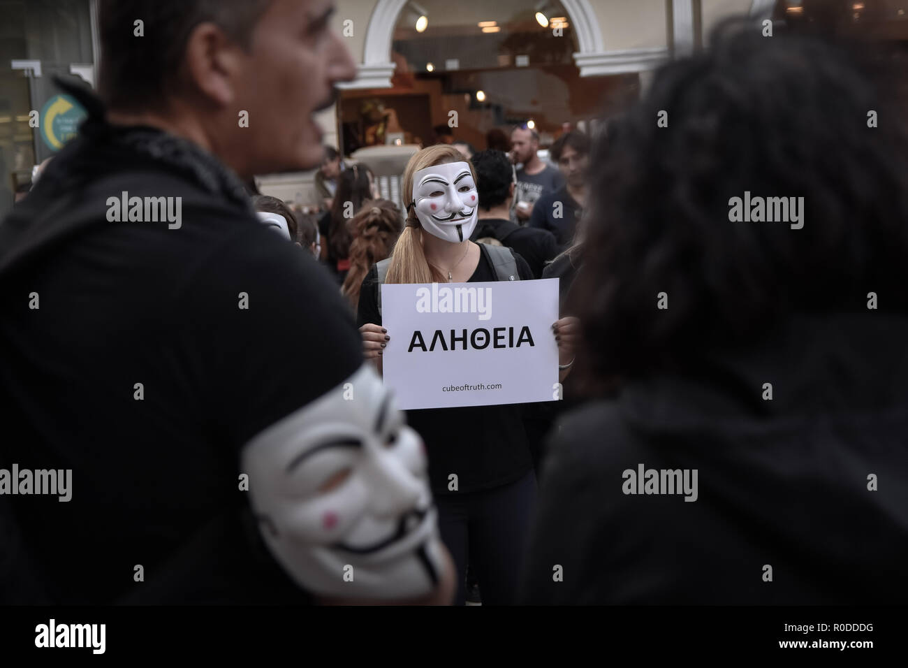 A participant seen standing wearing anonymous masks while holding a ...