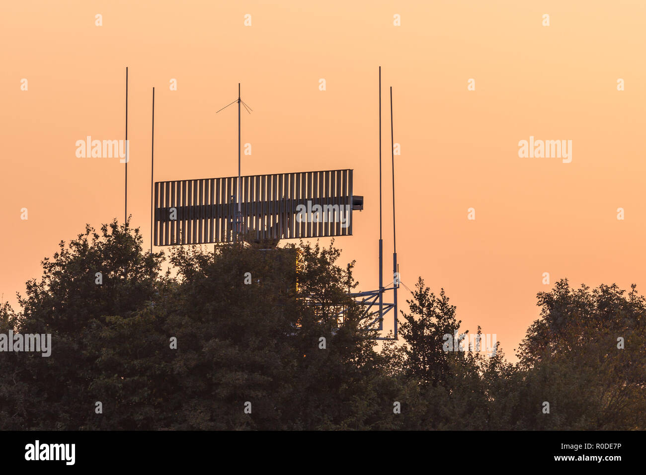 Radar antenna communication technology network hidden in bush during sunset. Stock Photo