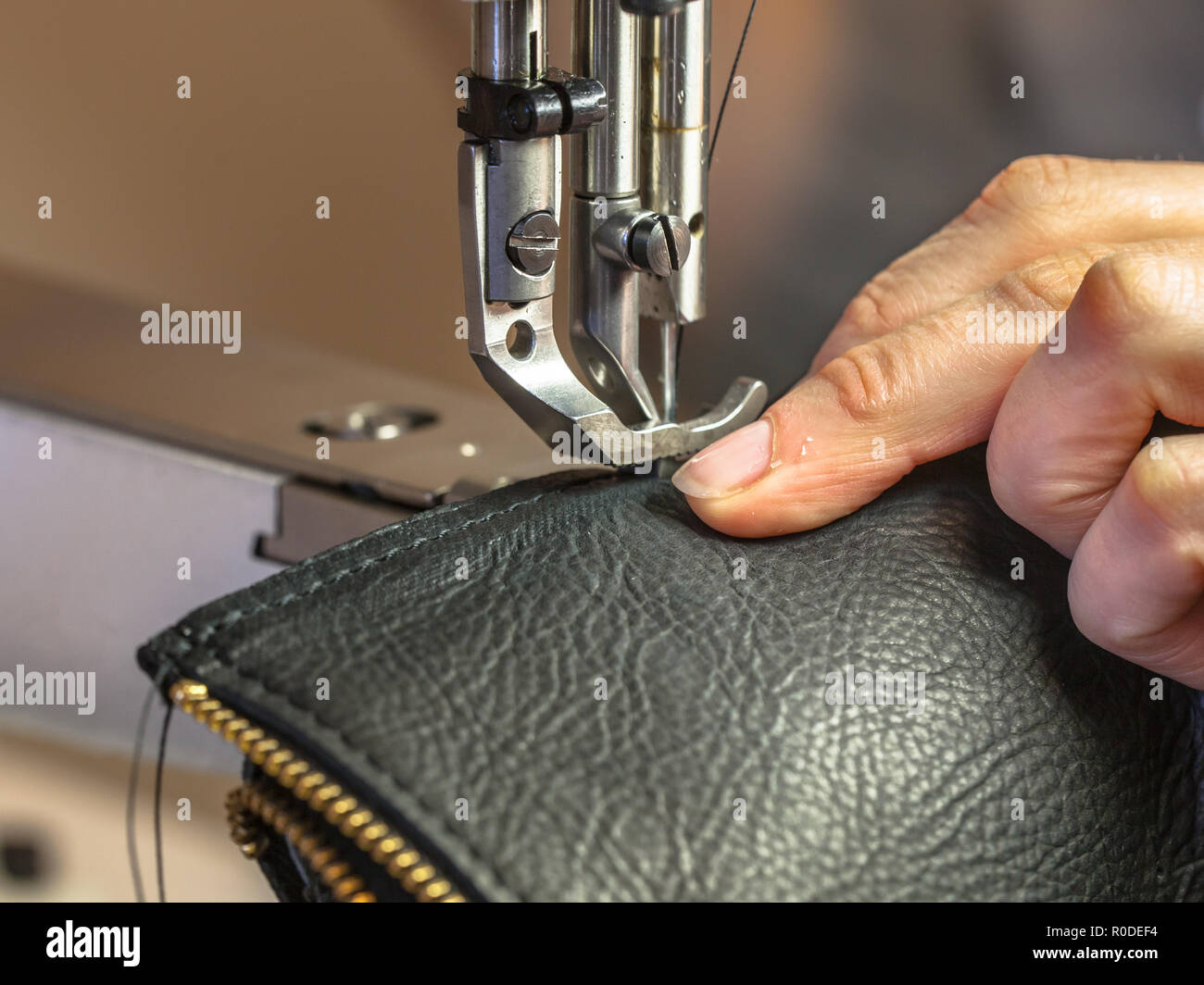 Leather sewing machine in action in a workshop with hands working on a  shoulder bag Stock Photo - Alamy