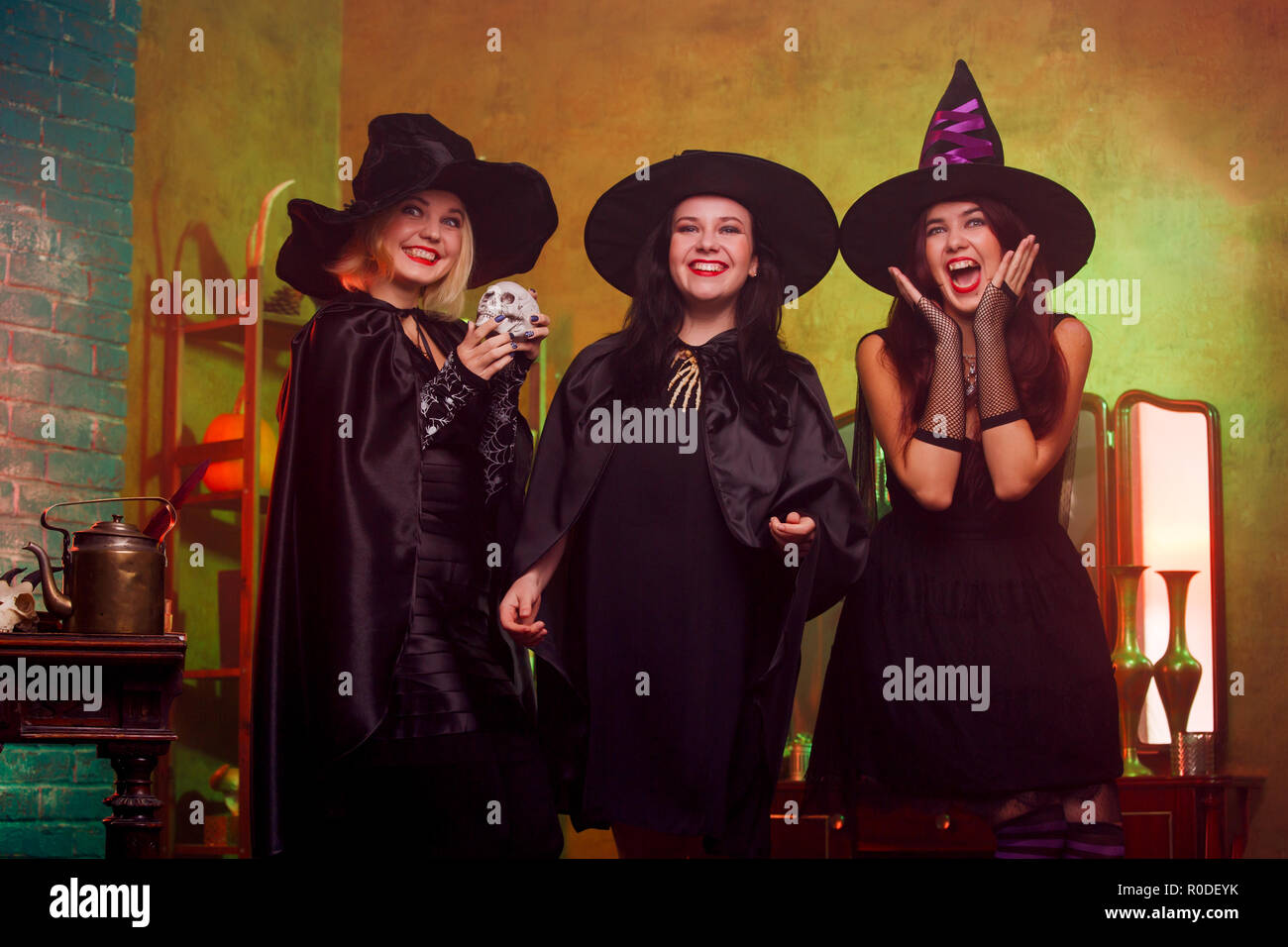 Picture of three witches in black hats in dark room against mirror and