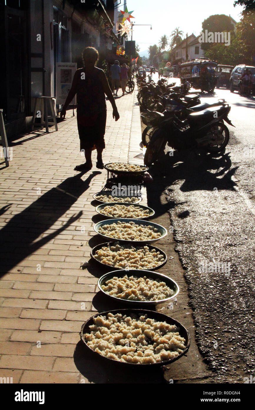 Sticky rice drying on the sidewalk in the sun at end of day, Luang Prabang, Laos Stock Photo