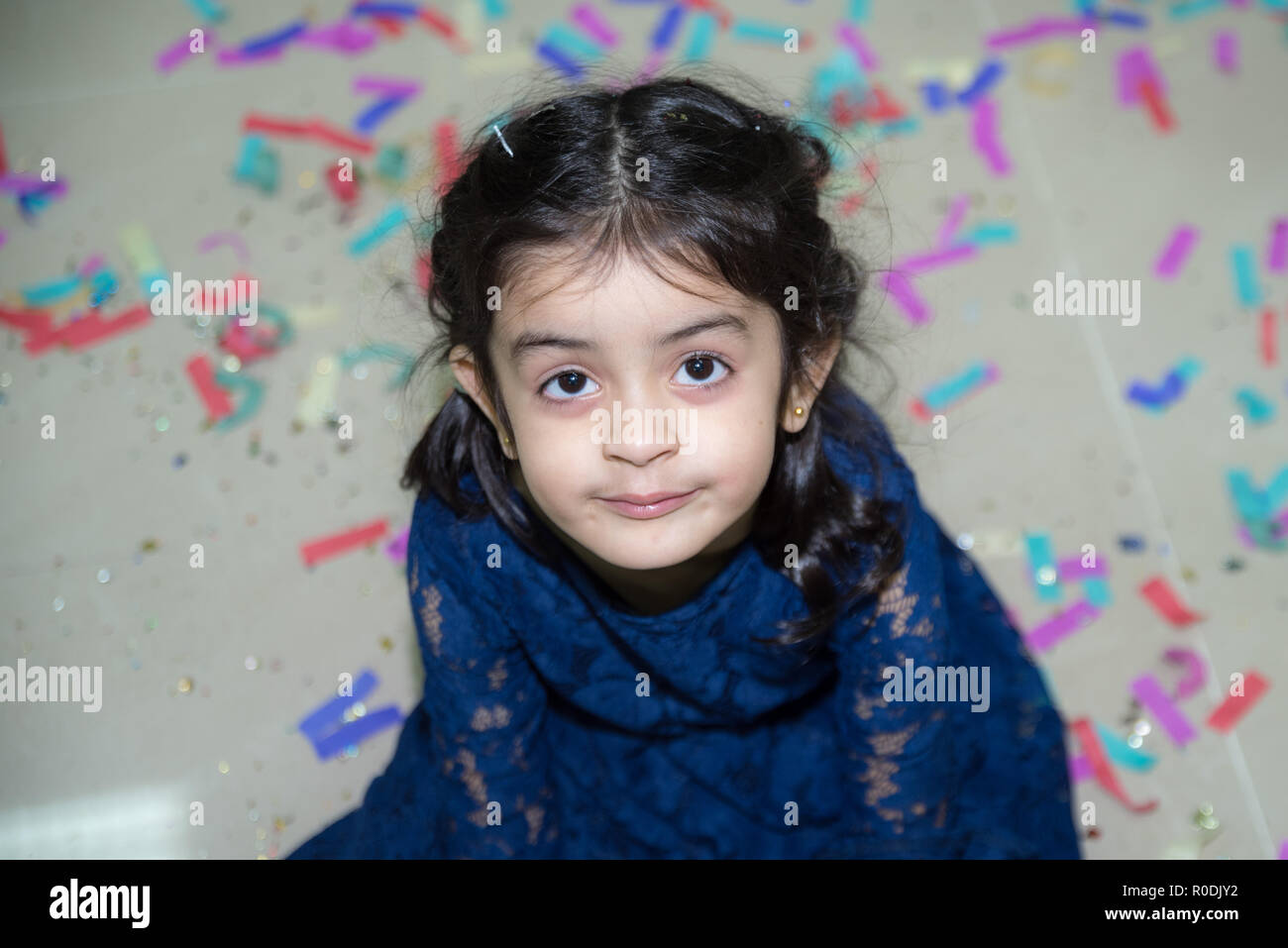 A little asian girl looking up and staring at camera on birthday celebration Stock Photo