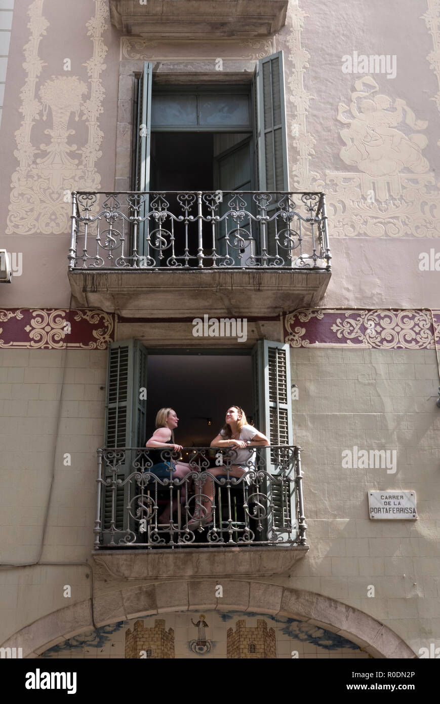 Two young women facing each other and  sitting on a small bacony, Barcelona, Spain Stock Photo