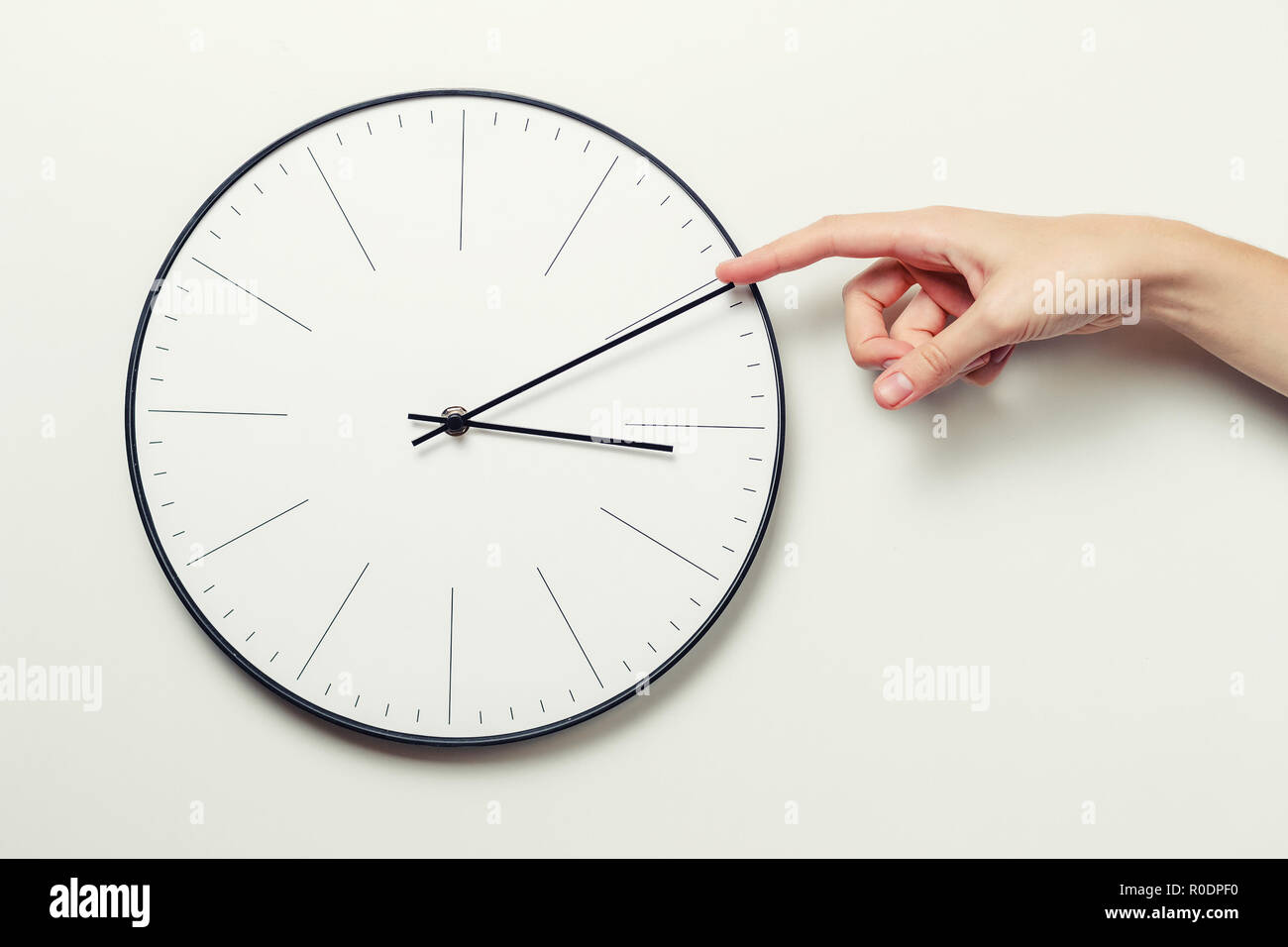 Woman hand stop time on round clock, time management and deadline