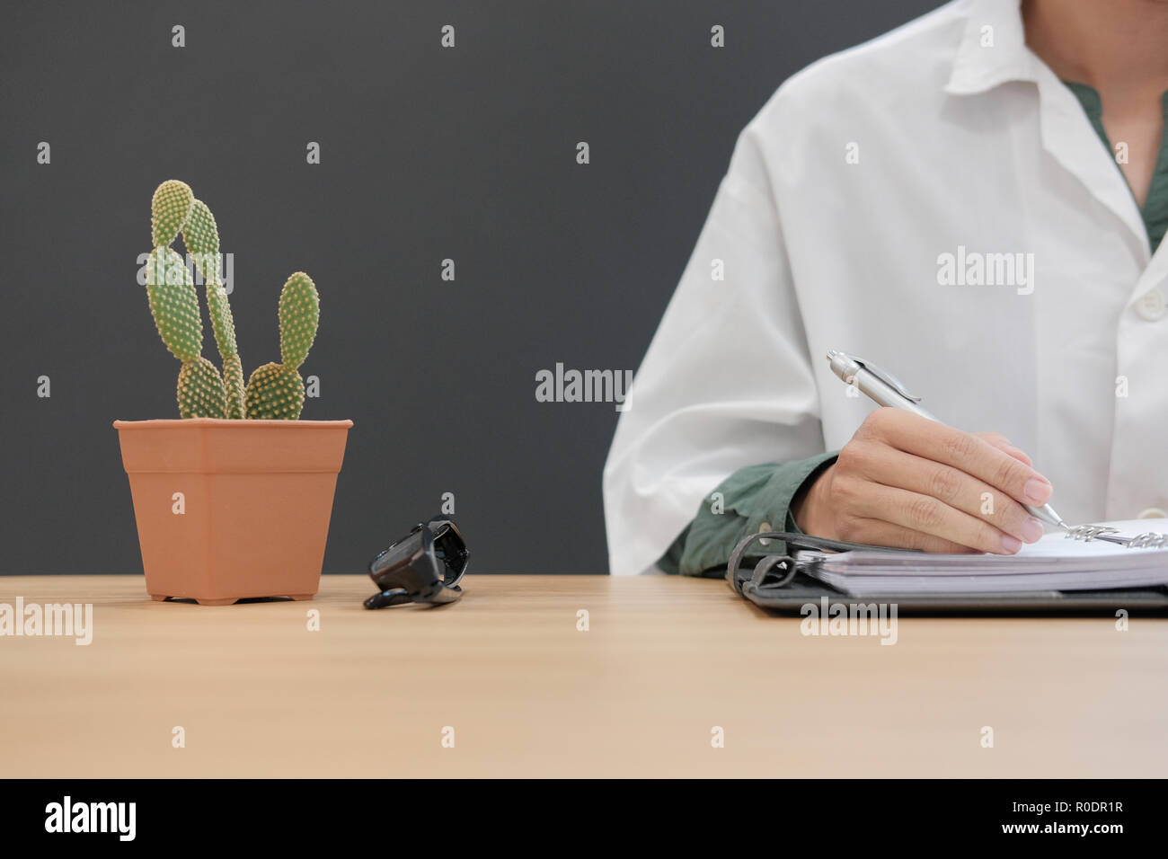 doctor working with cactus plant & eyeglasses on desk at clinic