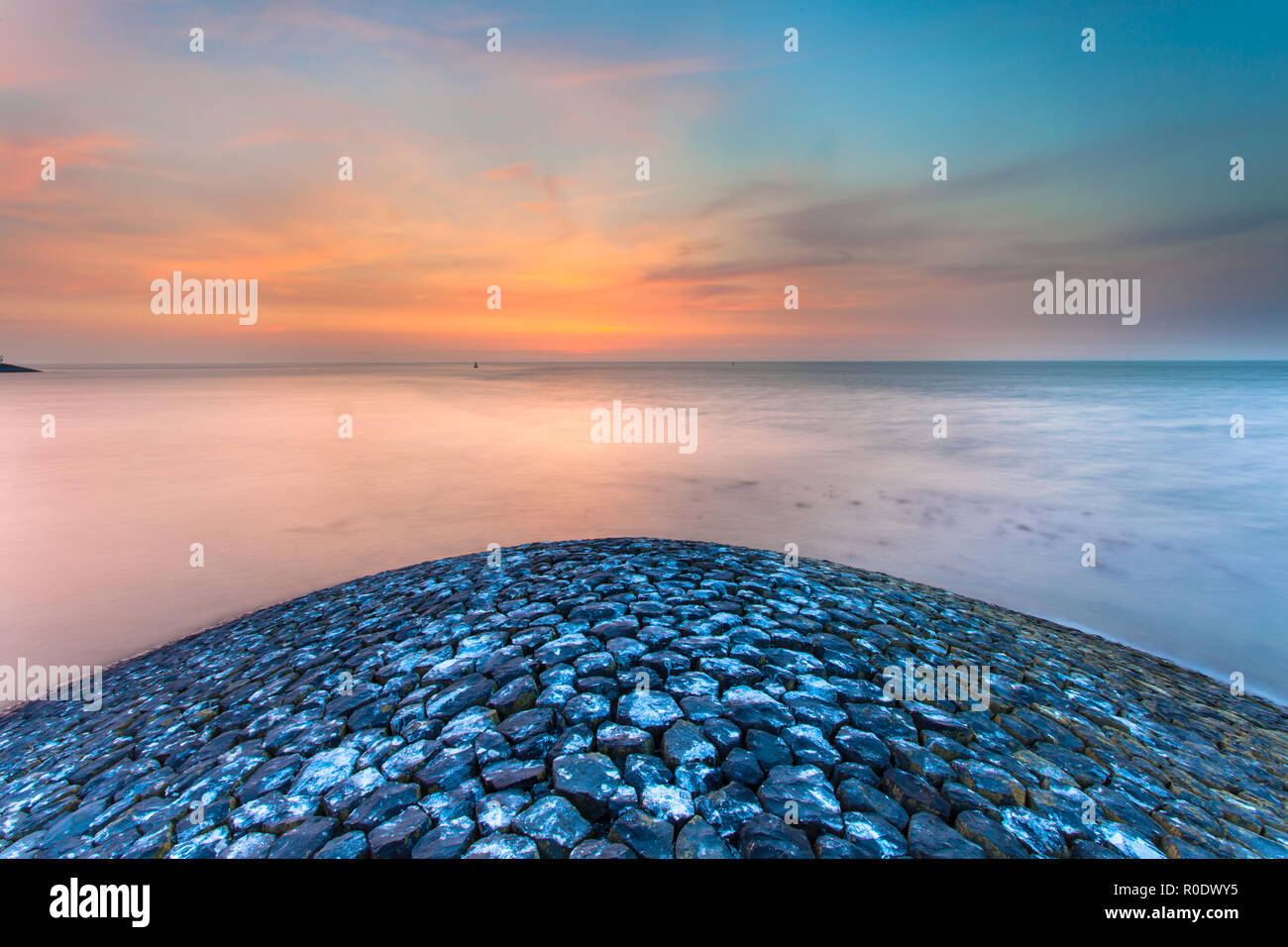 Sunset over Waddensea from the head of a Stone Waterflood Protection Pier Stock Photo